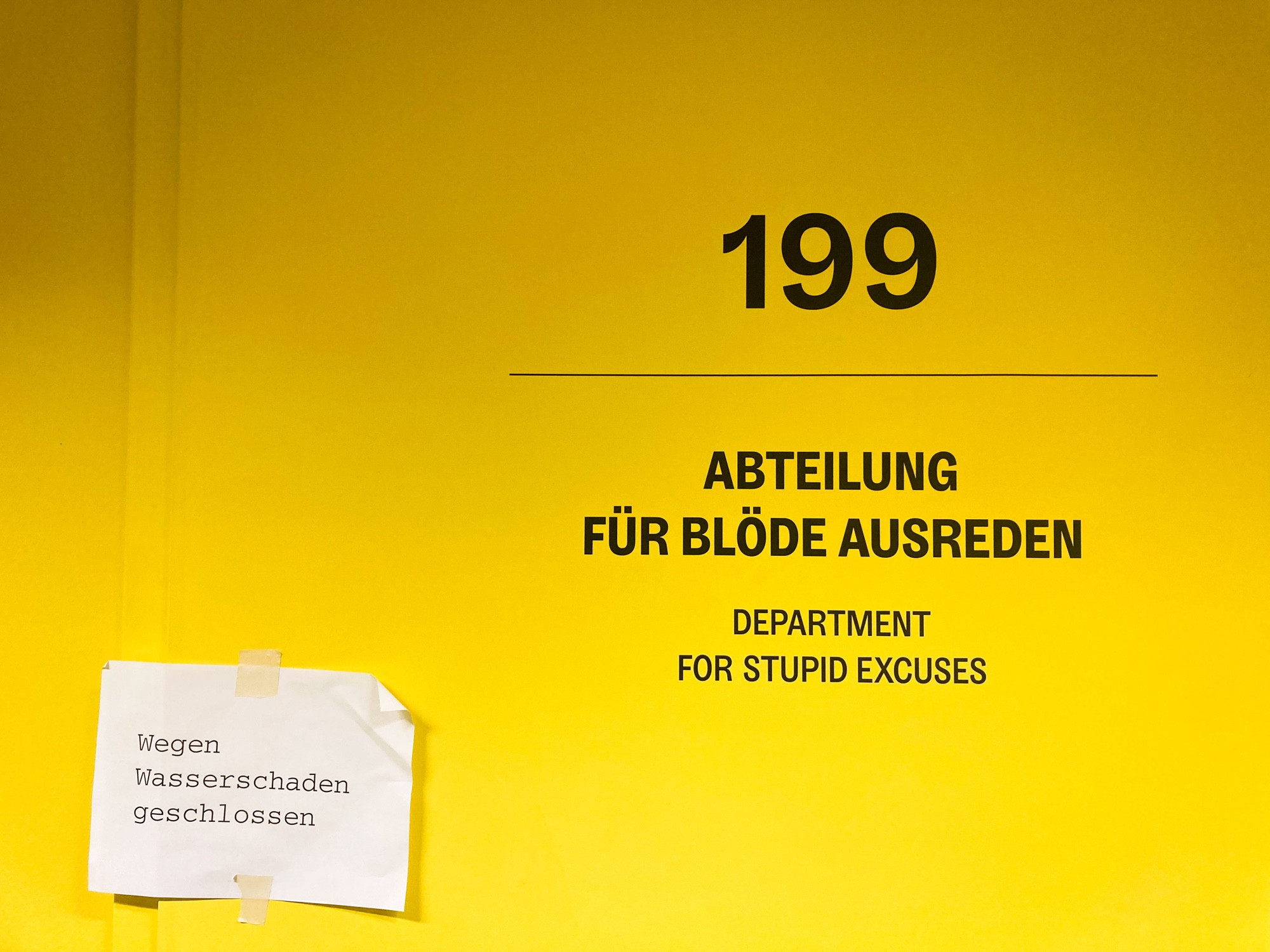 Signalgelbe Fläche mit schwarzer Schrift: 199 Abteilung für blöde Ausreden (Department for stupid excuses)
Darunter klebt ein kleiner Zettel: Wegen Wasserschaden geschlossen 