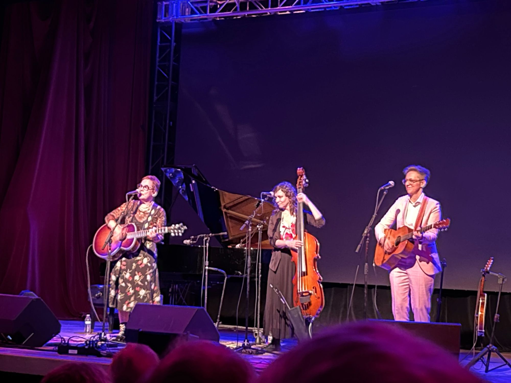 Three musicians on stage, left to right: Iris Dement with acoustic guitar, Liz Draper with stand up bass, Anne Egge with acoustic guitar