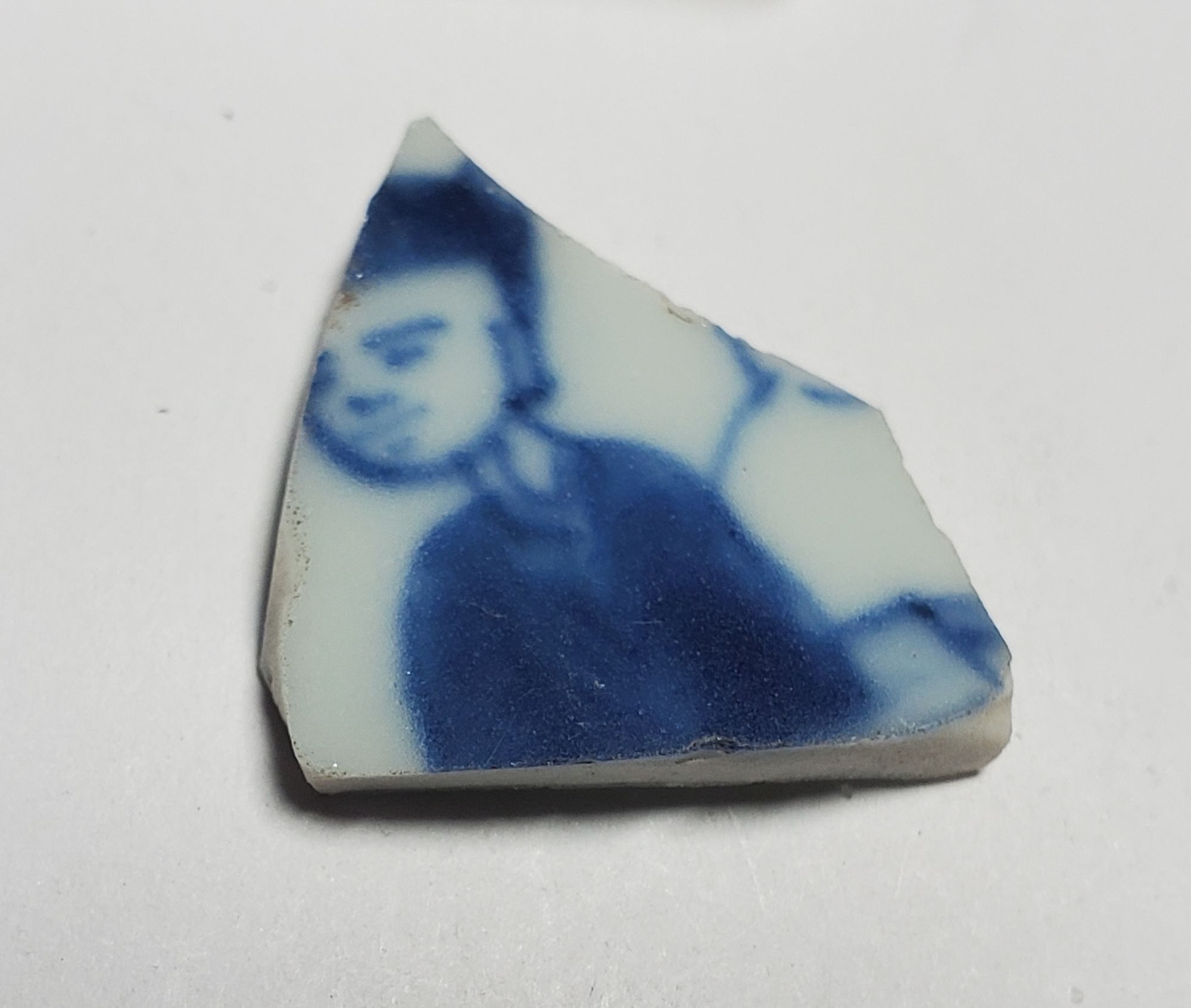 Porcelain sherd with the figure of an Asian man in a hat outlined in blue.