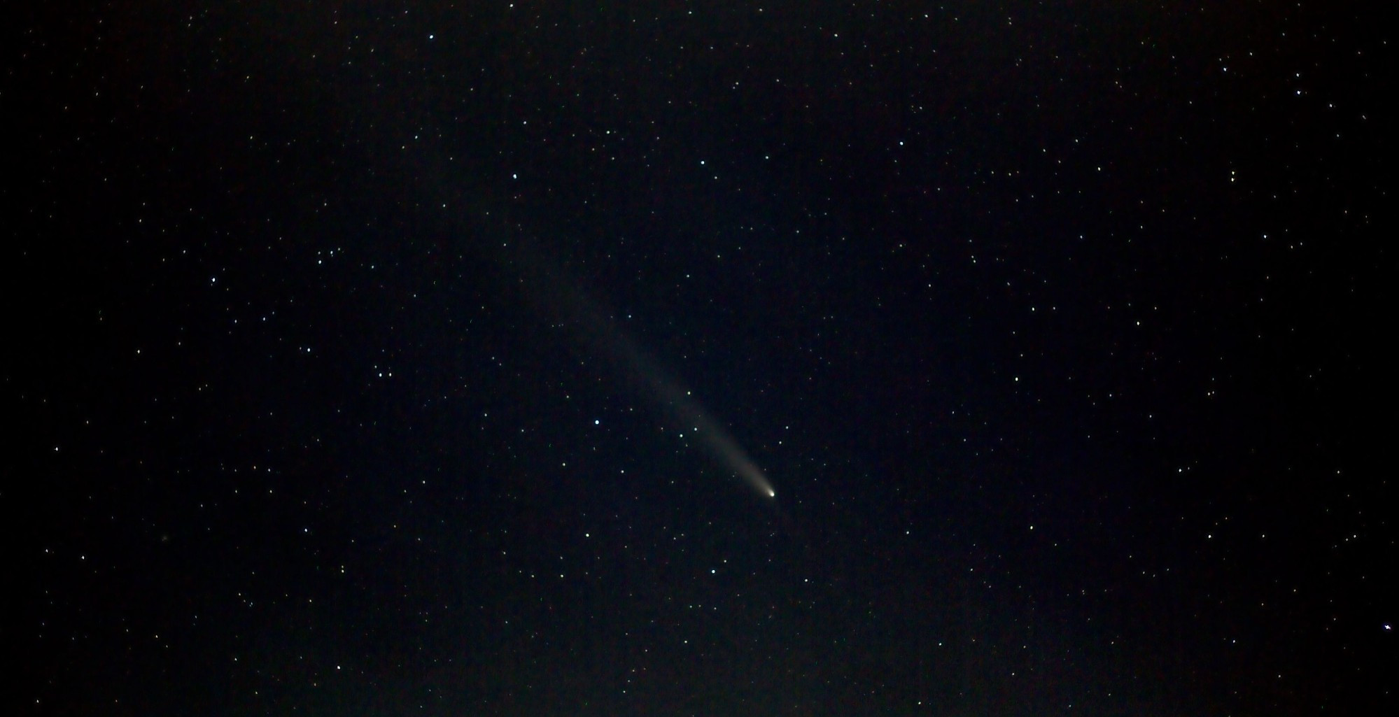 Comet with a long tail with numerous star dots and a noisy background. 