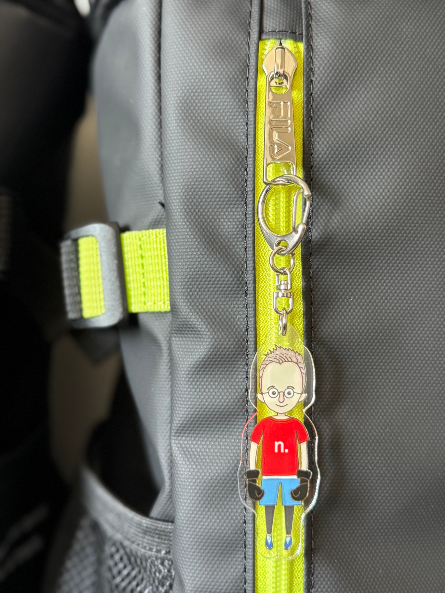 Detail of key ring with illustration of a male character in kickboxing sports gear, attached to a sports bag.