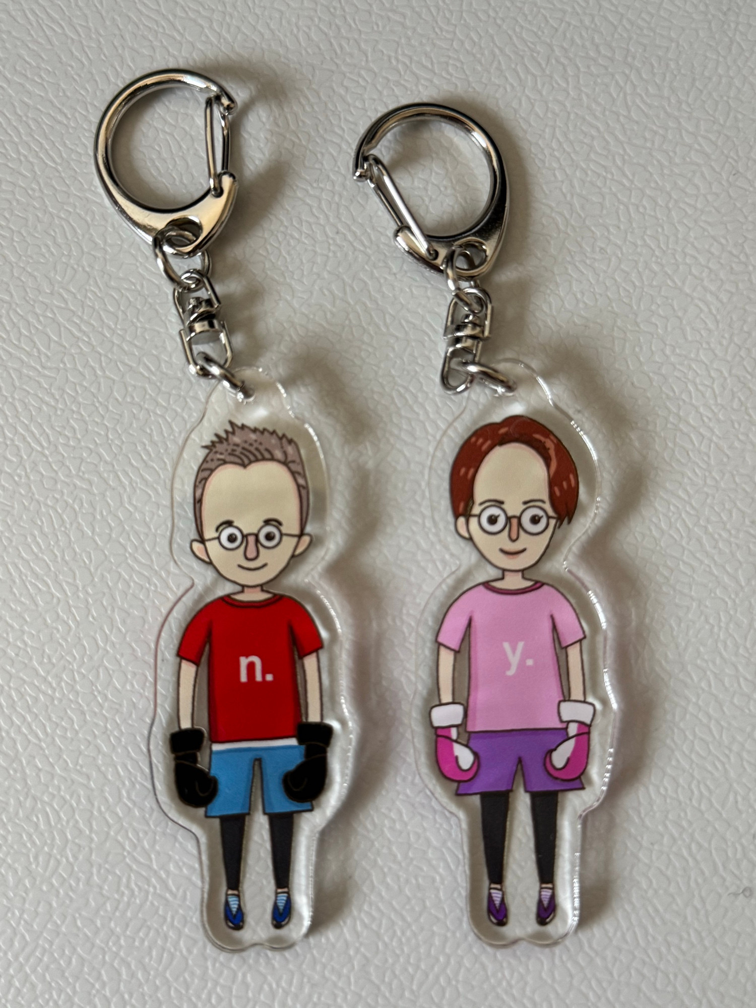 Two key rings with illustrations of a male and a female character in kickboxing sports gear.