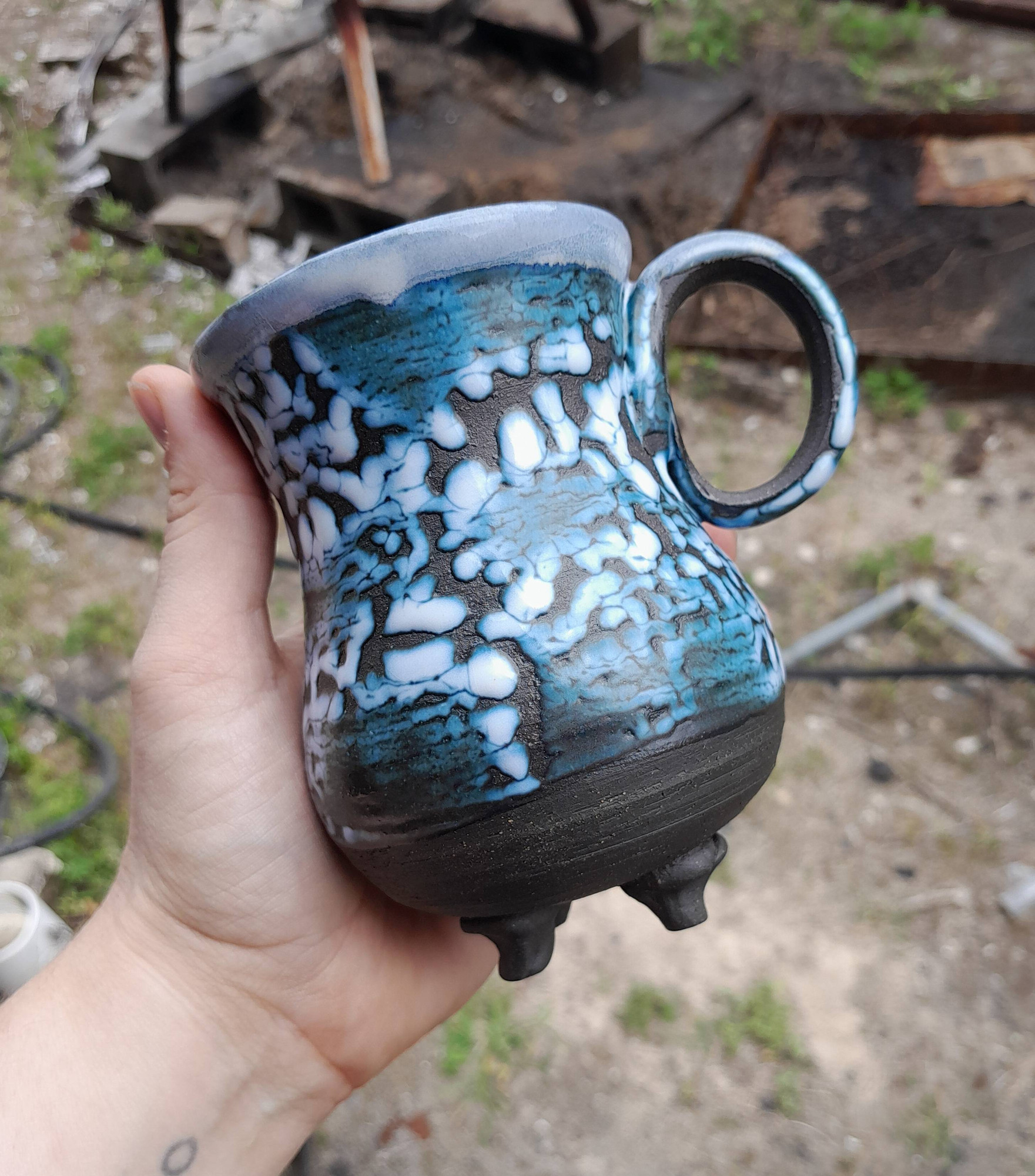 Mug made of black clay with a white crawl glaze and little feet