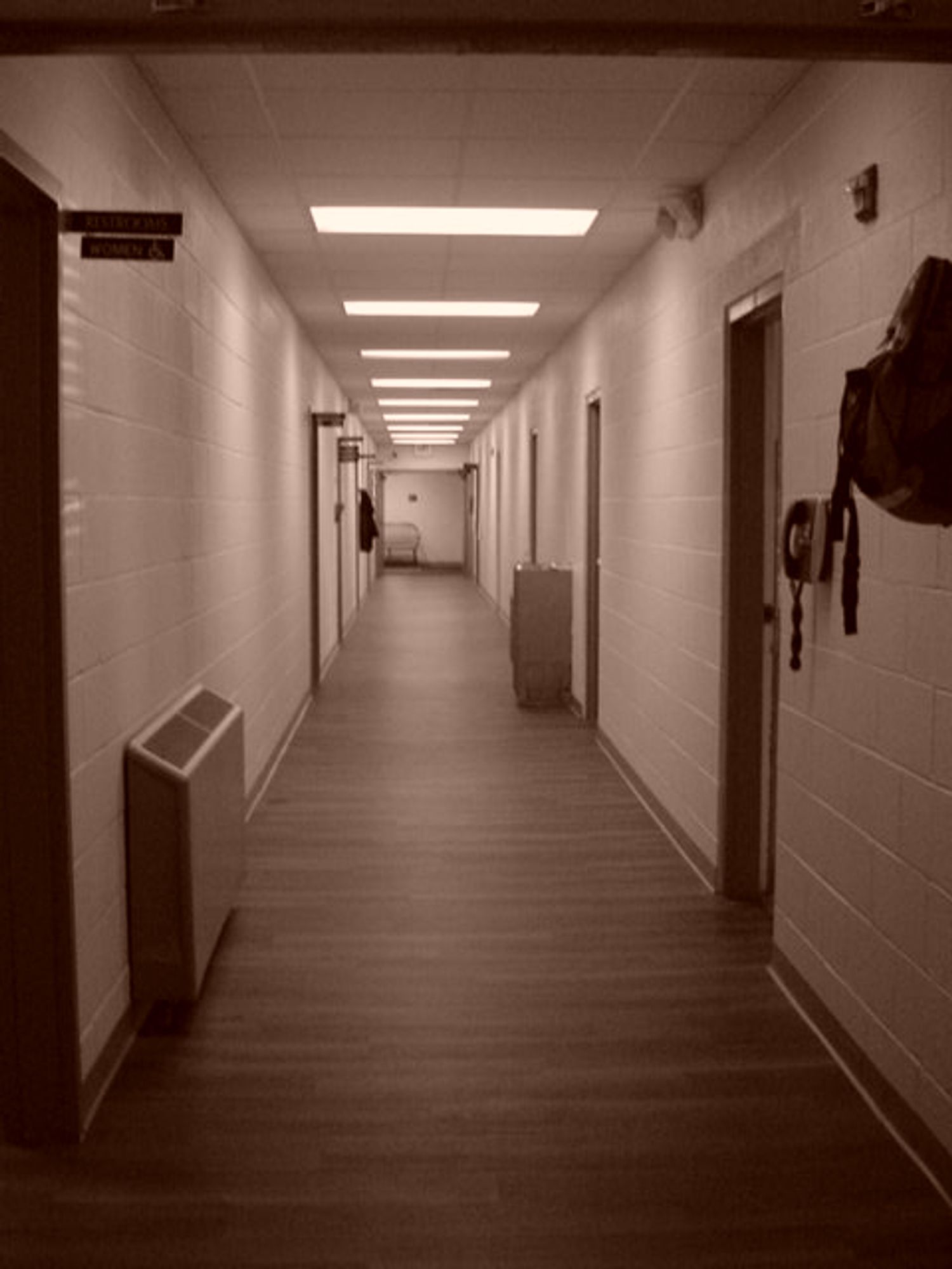 An unassuming, unmarked cinderblock hallway with florescent lights lighting it. This was taken with a sepia setting on a Sony Mavica MVC-FD200, the infamous floppy disk camera.