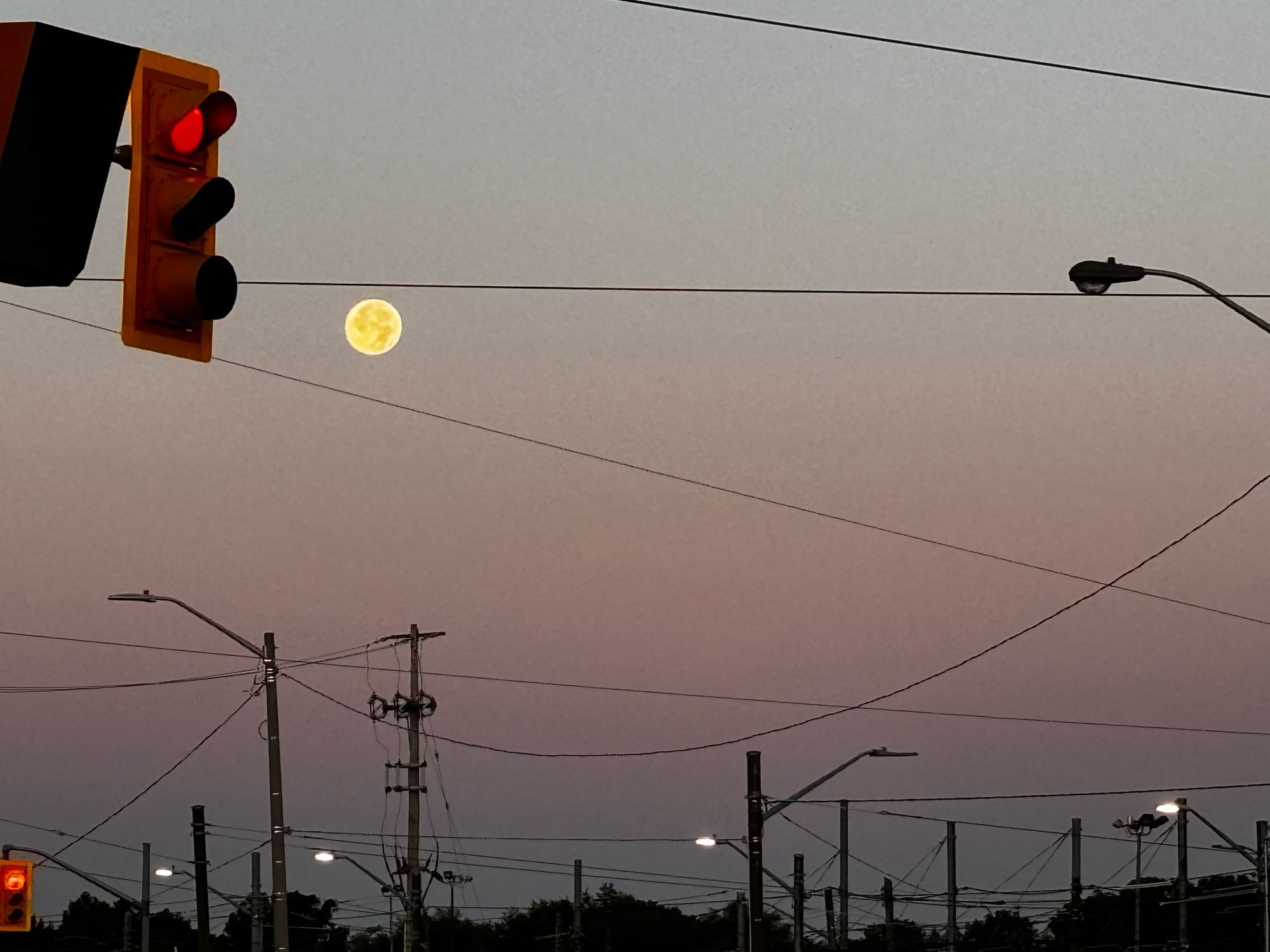 Moon, lights, and wires over a pink sunrise sky