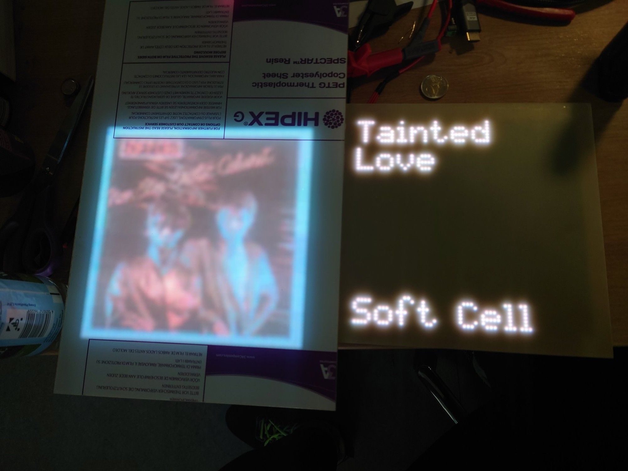 Two pixel displays, the left one displaying an album cover and the right one the track name and artist.