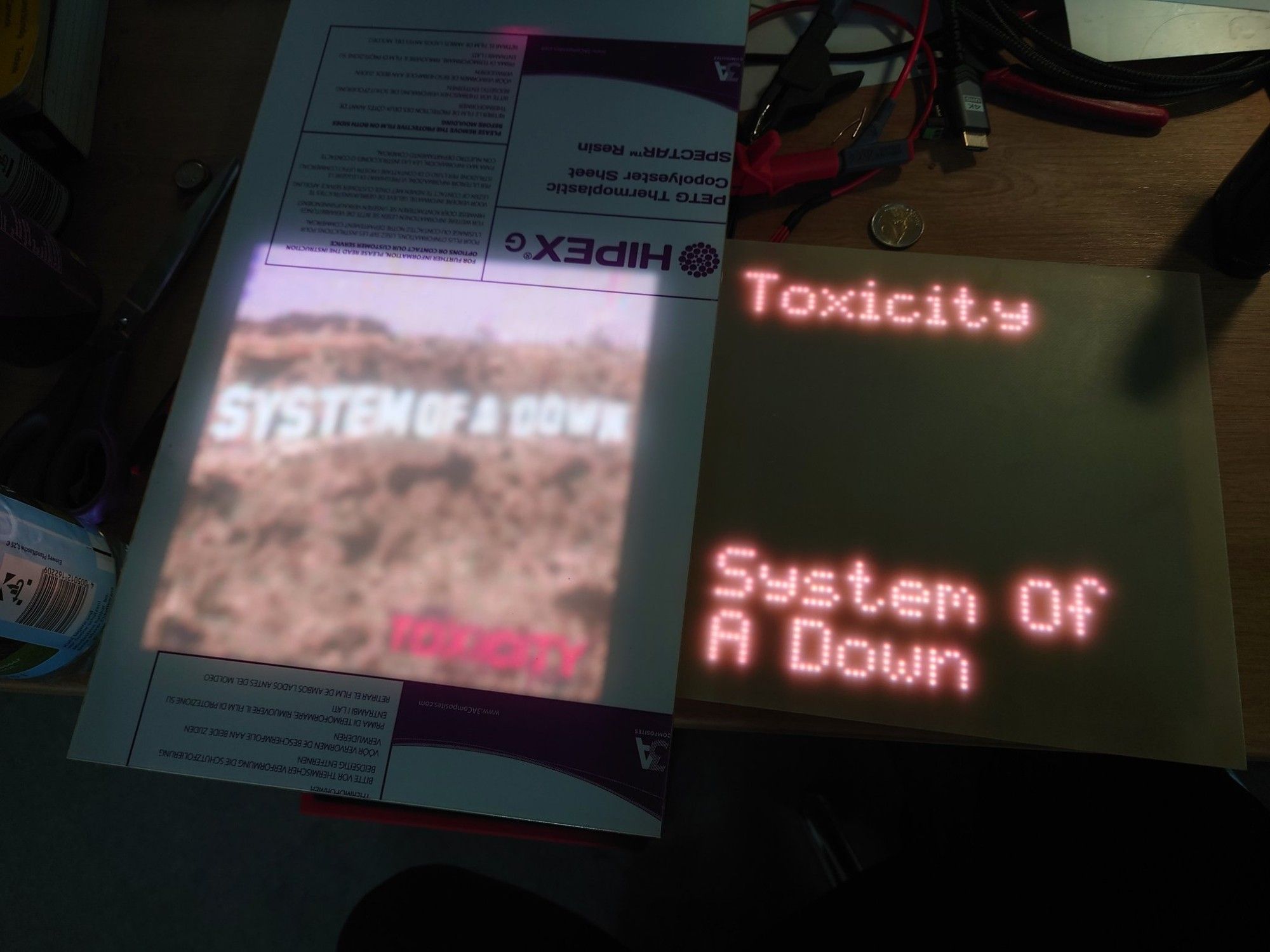 Two pixel displays, the left one displaying an album cover and the right one the track name and artist.