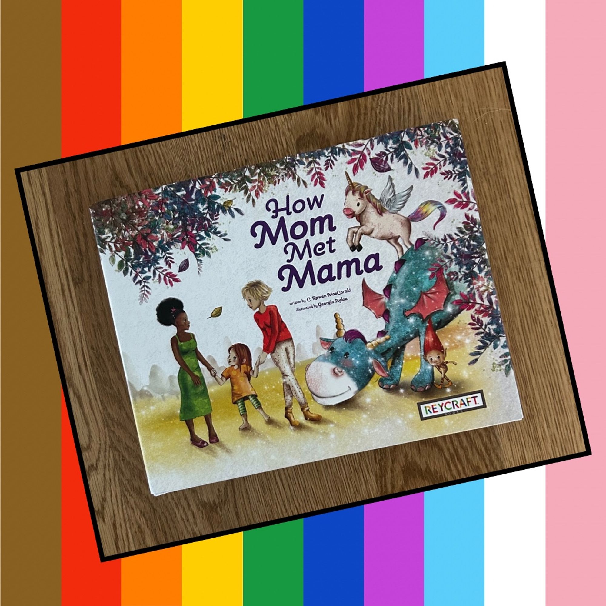 Cover of a picture book HOW MOM MET MAMA with two women holding one hand each of a small child and a cartoon dragon , elf, and unicorn looking on.