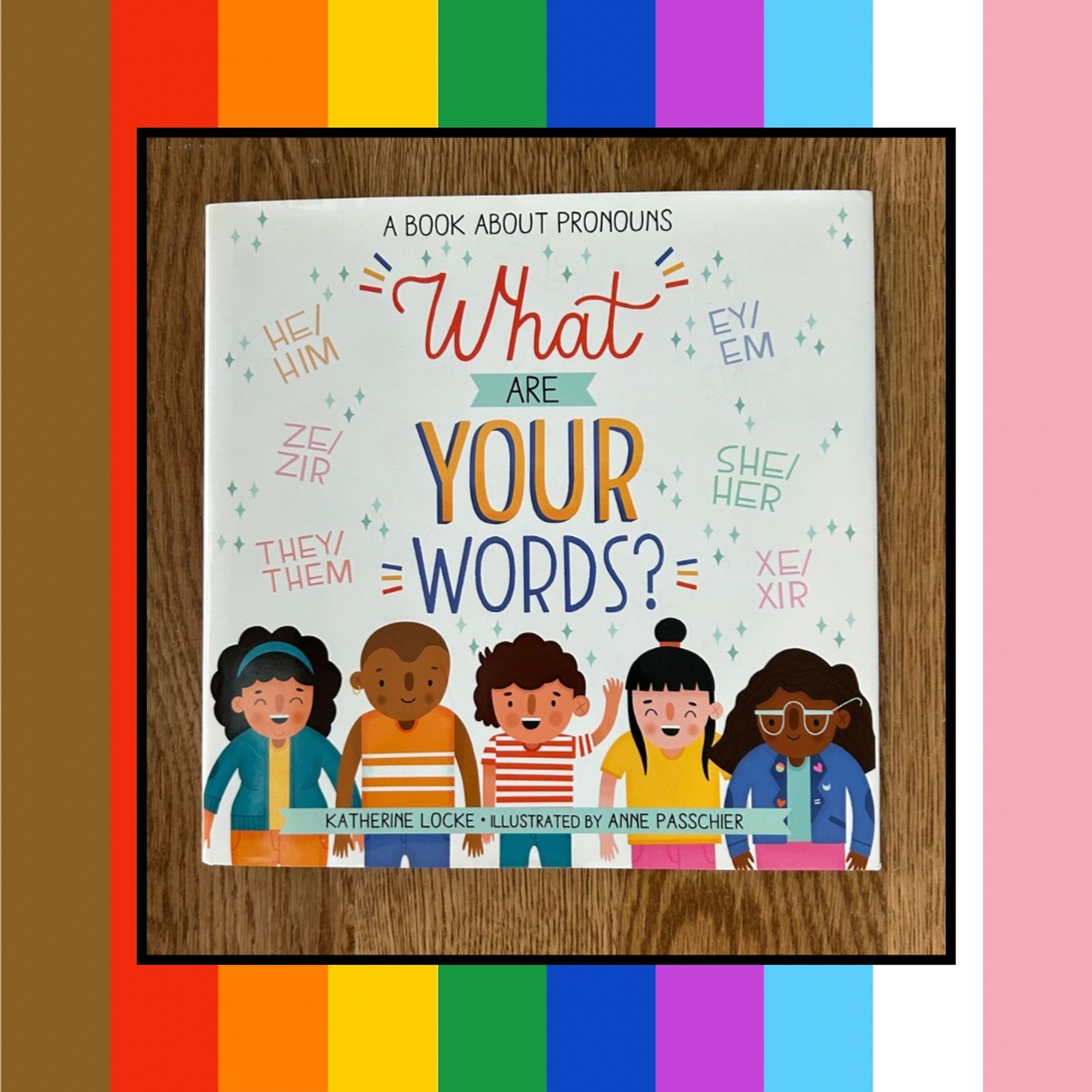 Rainbow striped graphic with a picture of a picture book called WHAT ARE YOUR WORDS? by Katherine Locke, illustrated by Andy Passcher on it. The cover shows five kids facing forward with lots of different pronouns written around them.