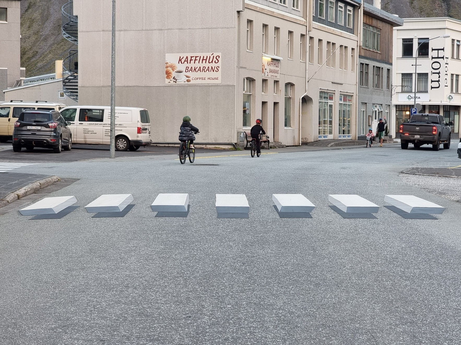 A street scene with a pedestrian crossing that appears to be solid white blocks floating above the tarmac