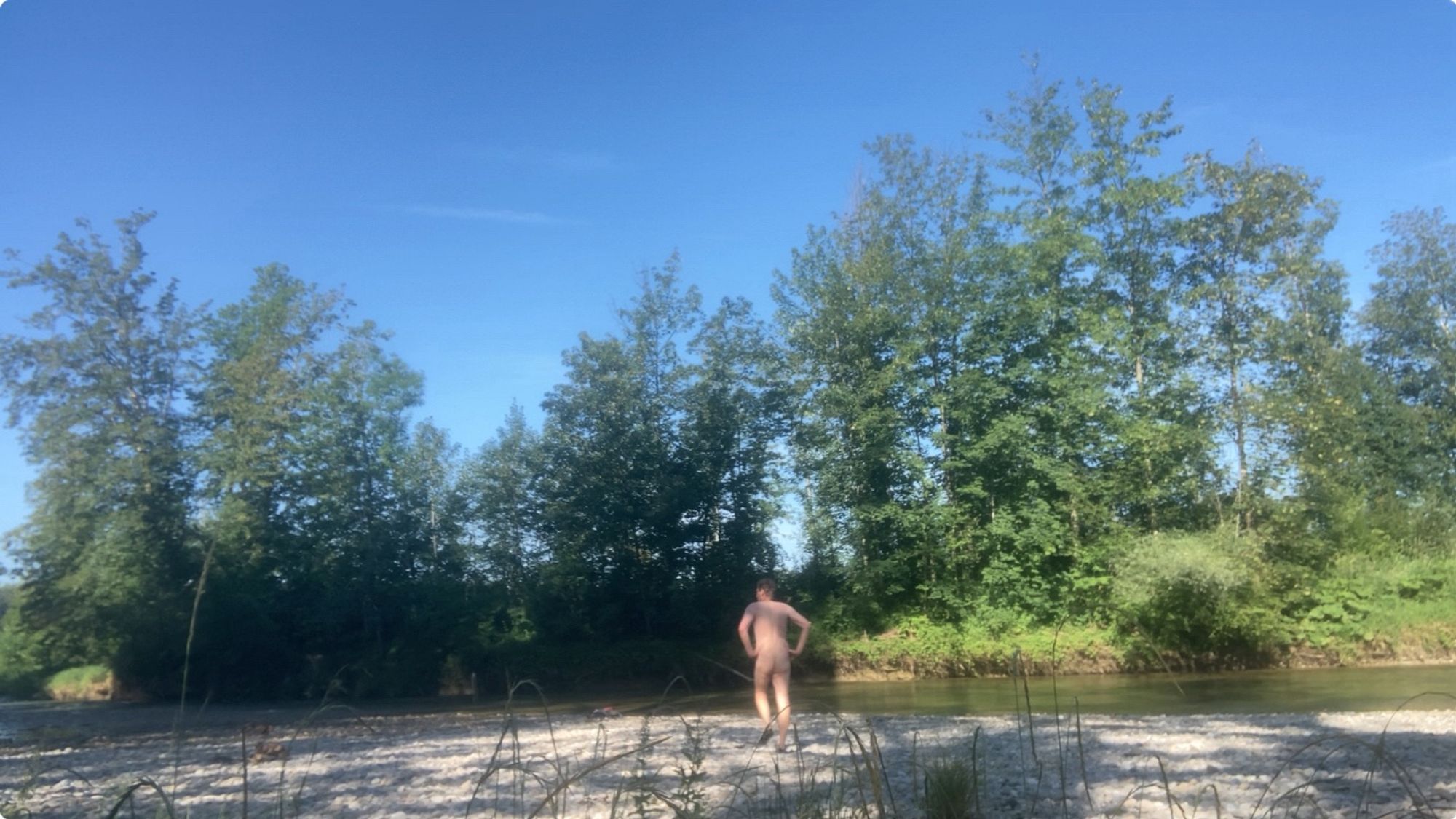 Nude man (back) at a river.