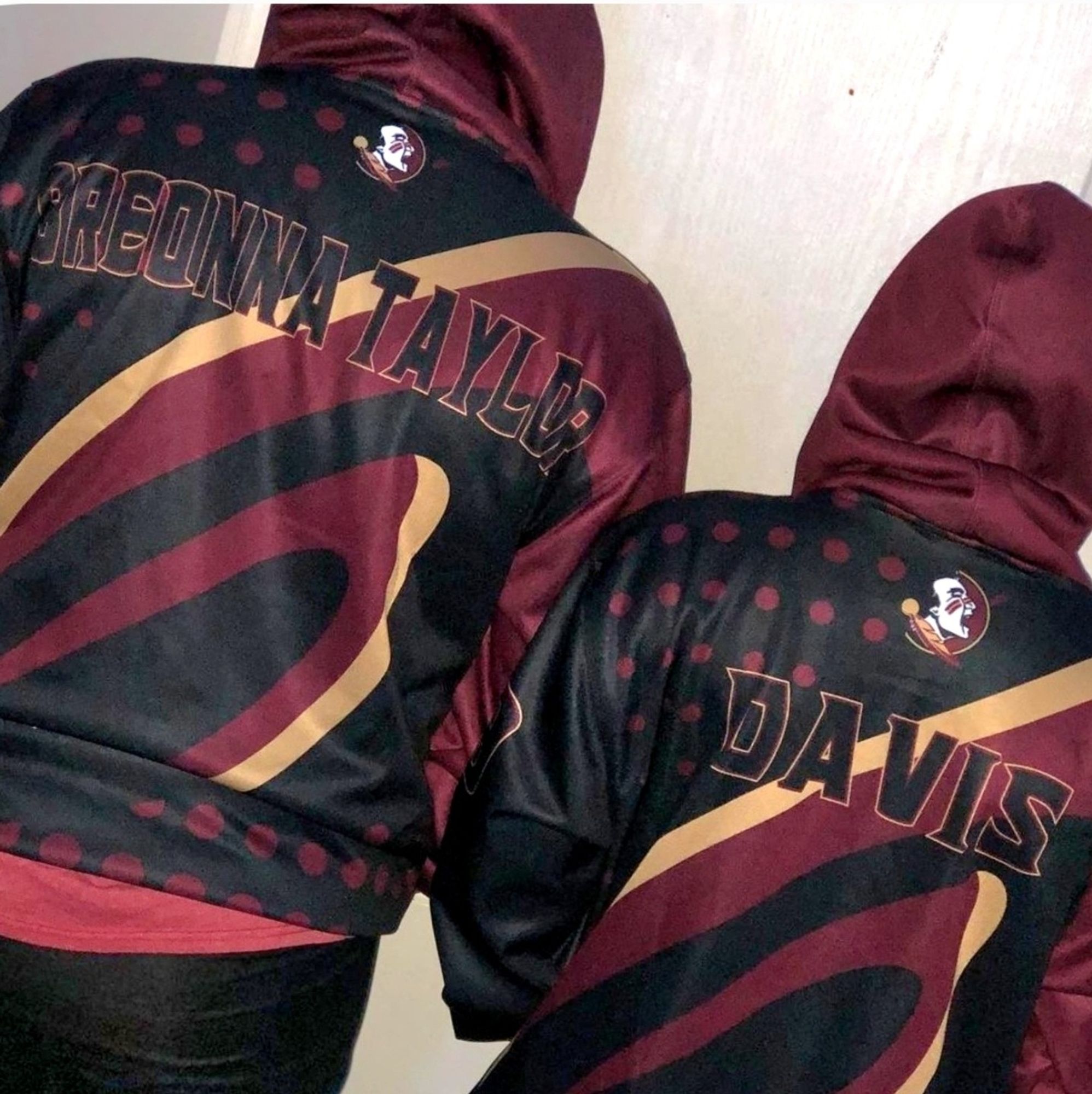 two preteens with backs turned wearing hooded sports jackets, one is embroidered with "breonna taylor" and the other "davis".