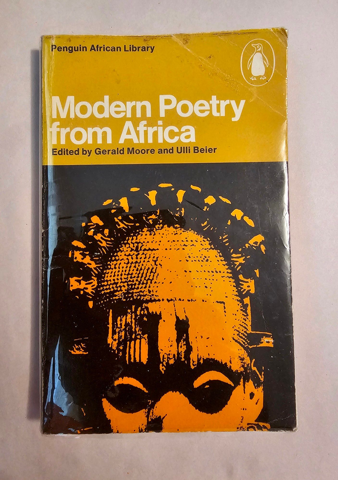 bookcover: dark yellow & black background with white type over the yellow that says "modern poetry from africa" and the top half of a heavily contrasted african mask saturated in orange over the black.