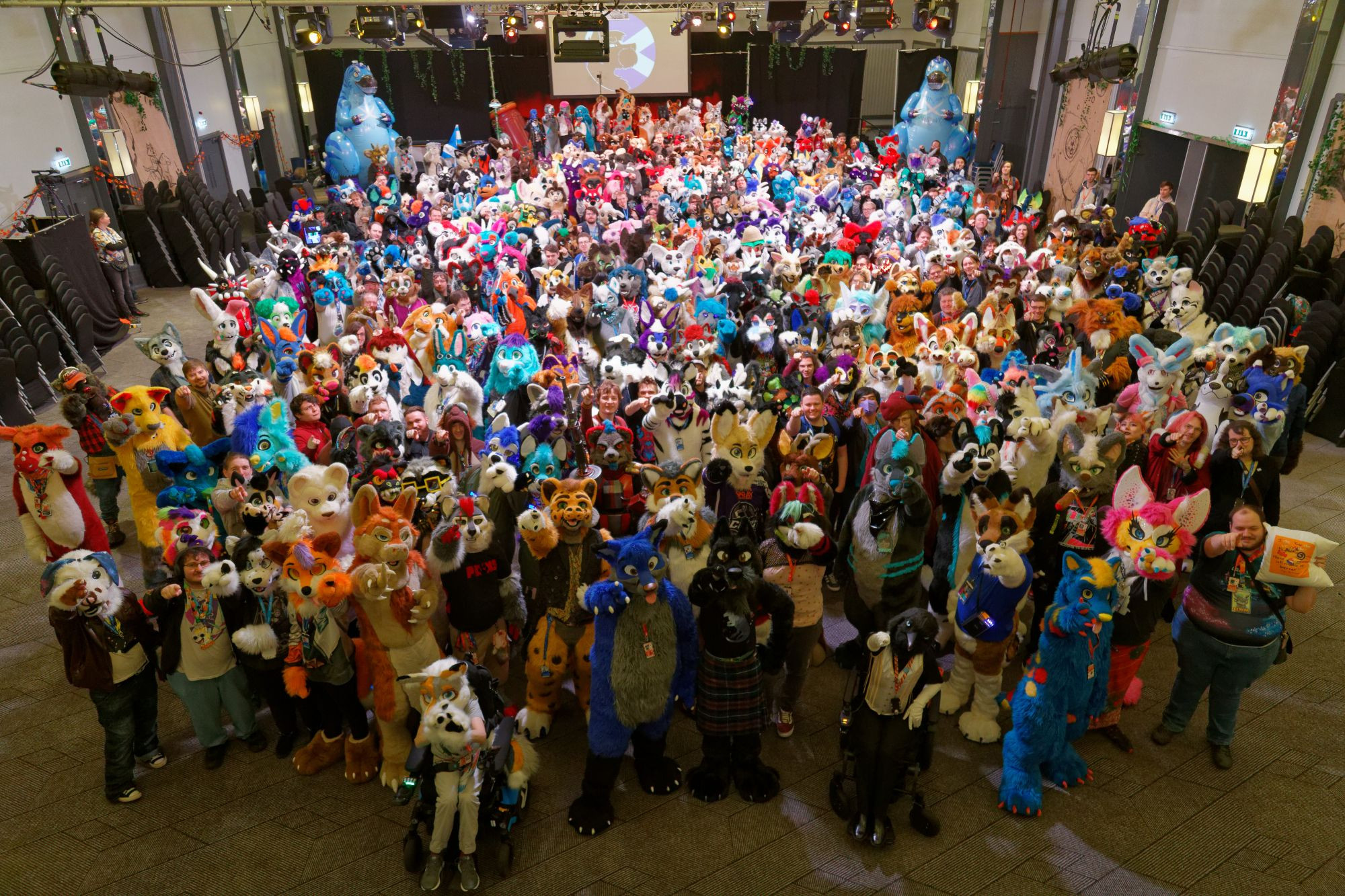 A collection of hundreds of fursuiters and a few other attendees, all pointing at the camera, from the Scotiacon 2024 Group Photo.