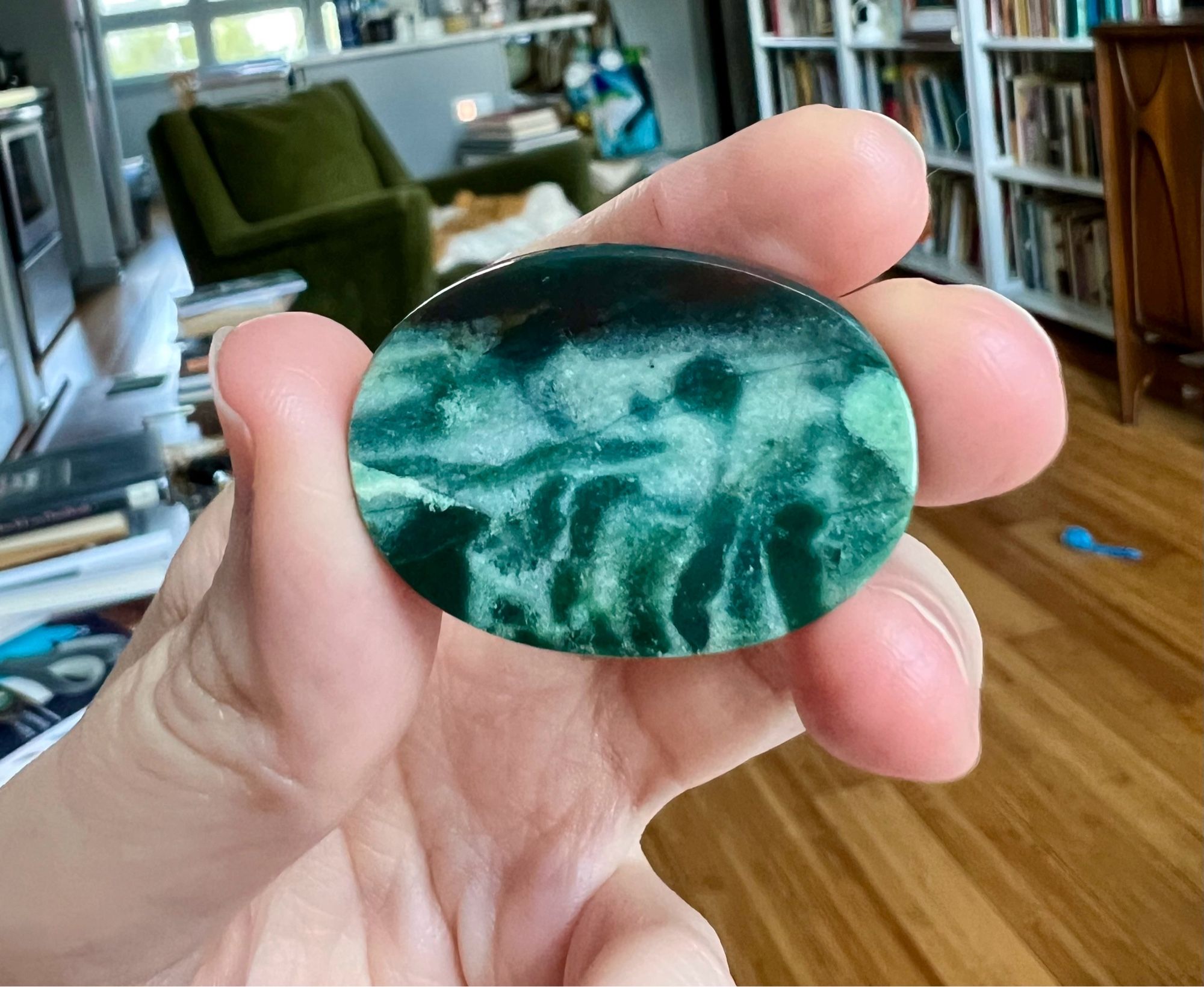 a ball of fingers holding a green, gray and black jasper cabochon