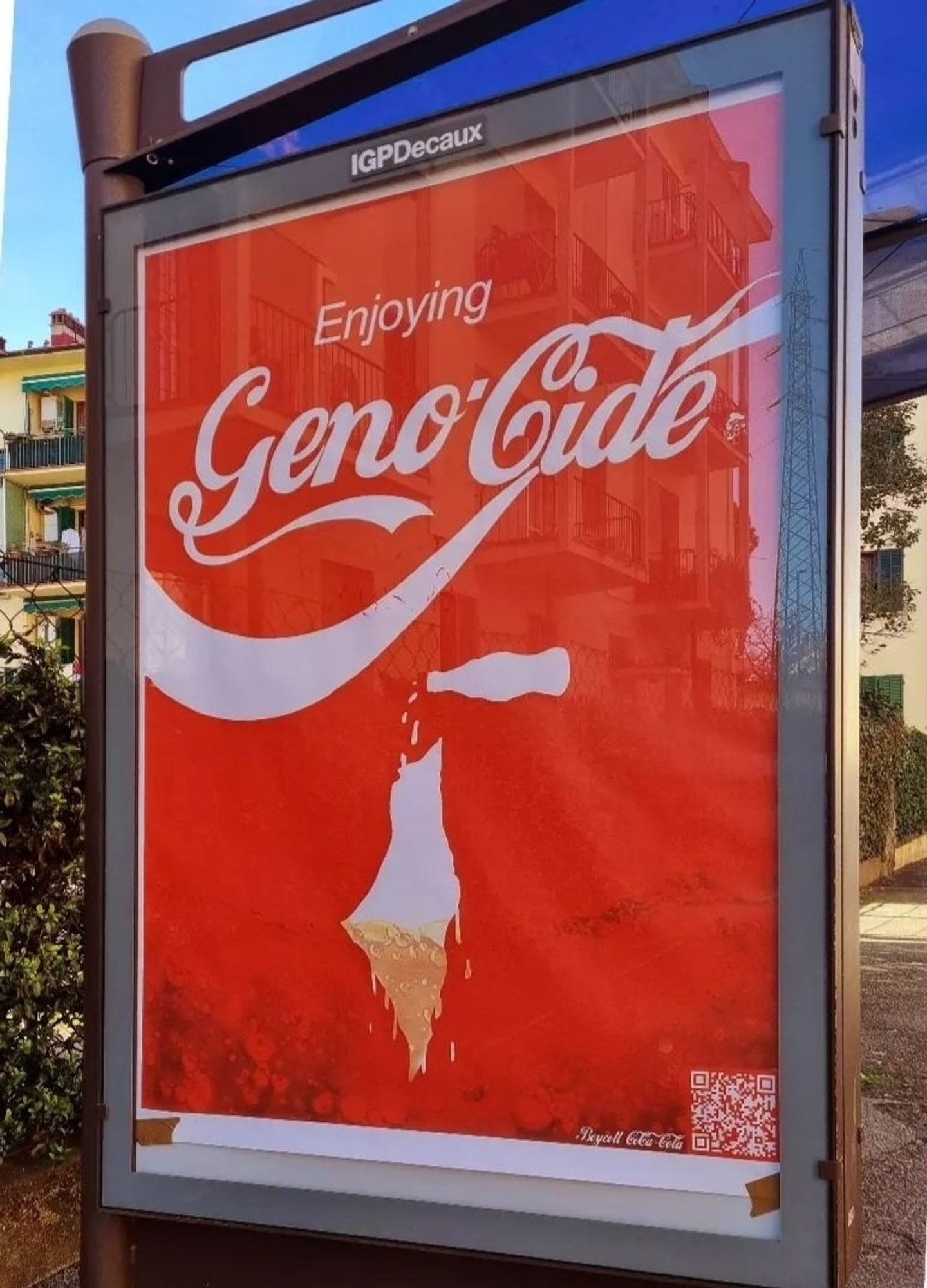 Coca-Cola themed poster on an ad frame that says "Enjoying Geno-cide"