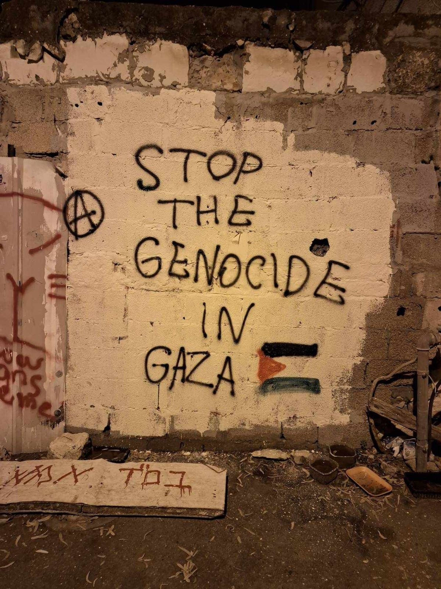 "Stop the genocide in Gaza" and an anarchy symbol and Palestinian flag written on a wall with spray paint