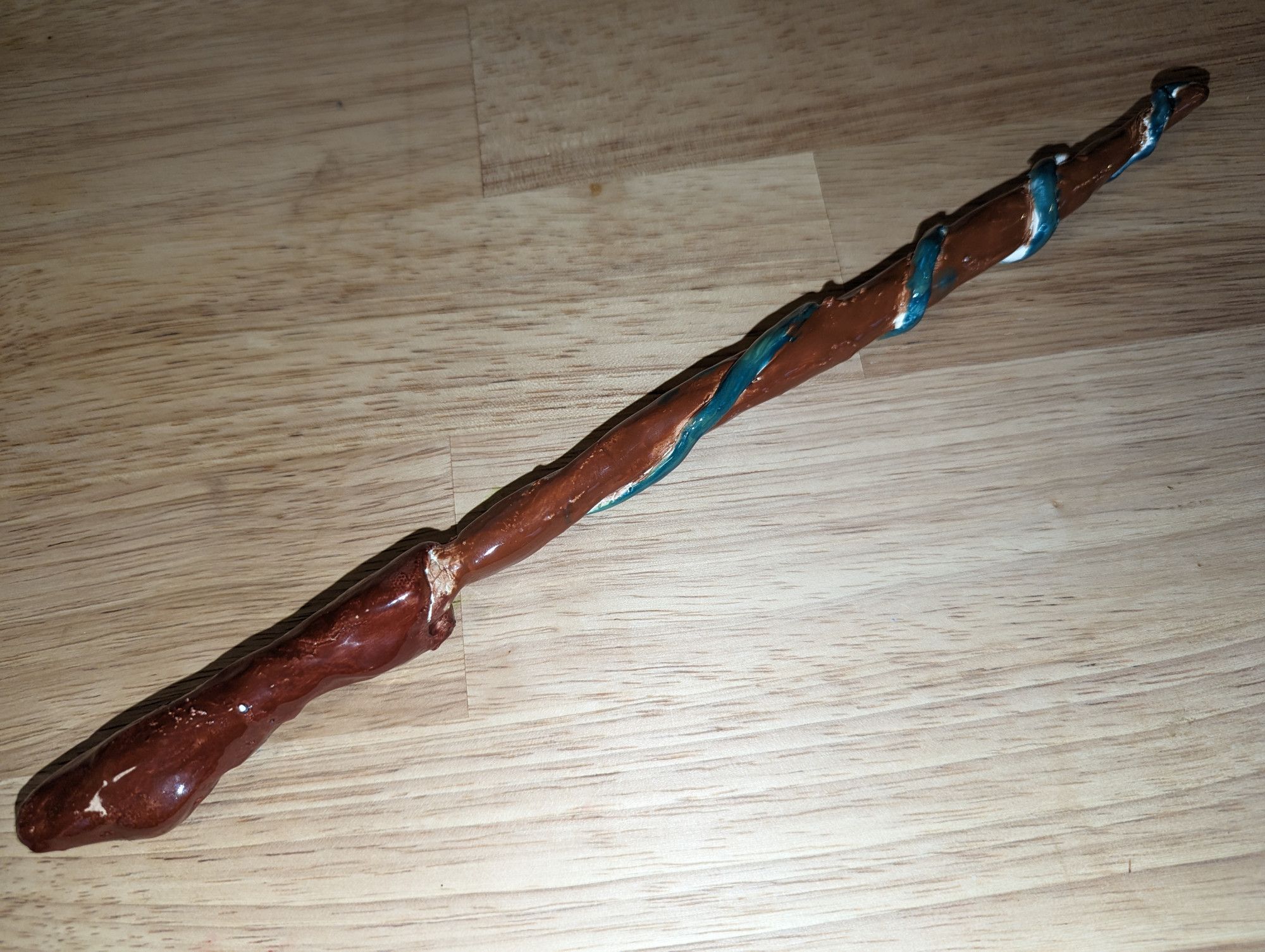 Magic wand made of fired clay, appearing as a wooden stick with a green vine wrapped around it. Made by Li'l Doodler as fanart for Kids on Brooms.