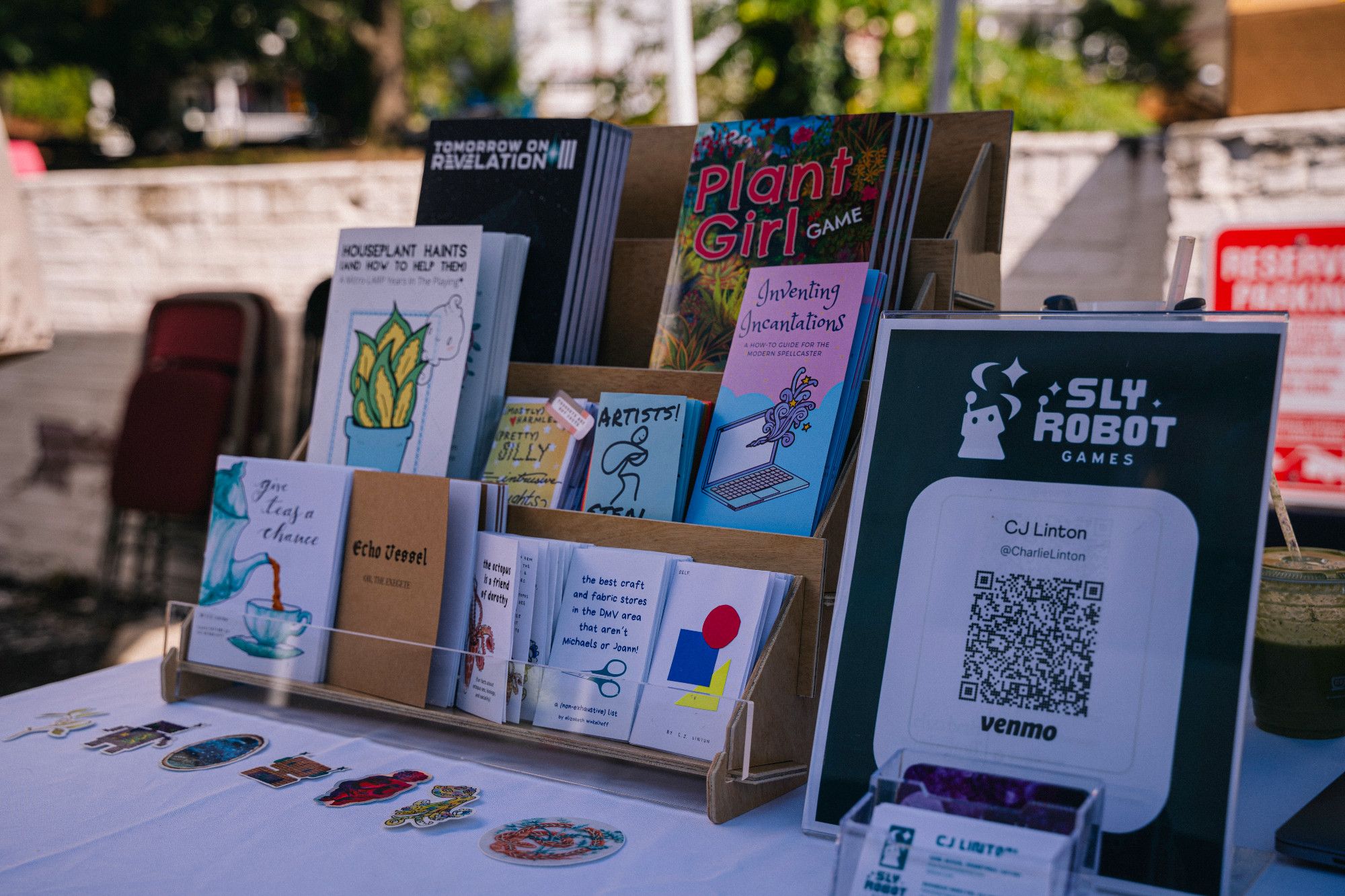 A table stand showing multiple zine-sized games offered by Sly Robot Games