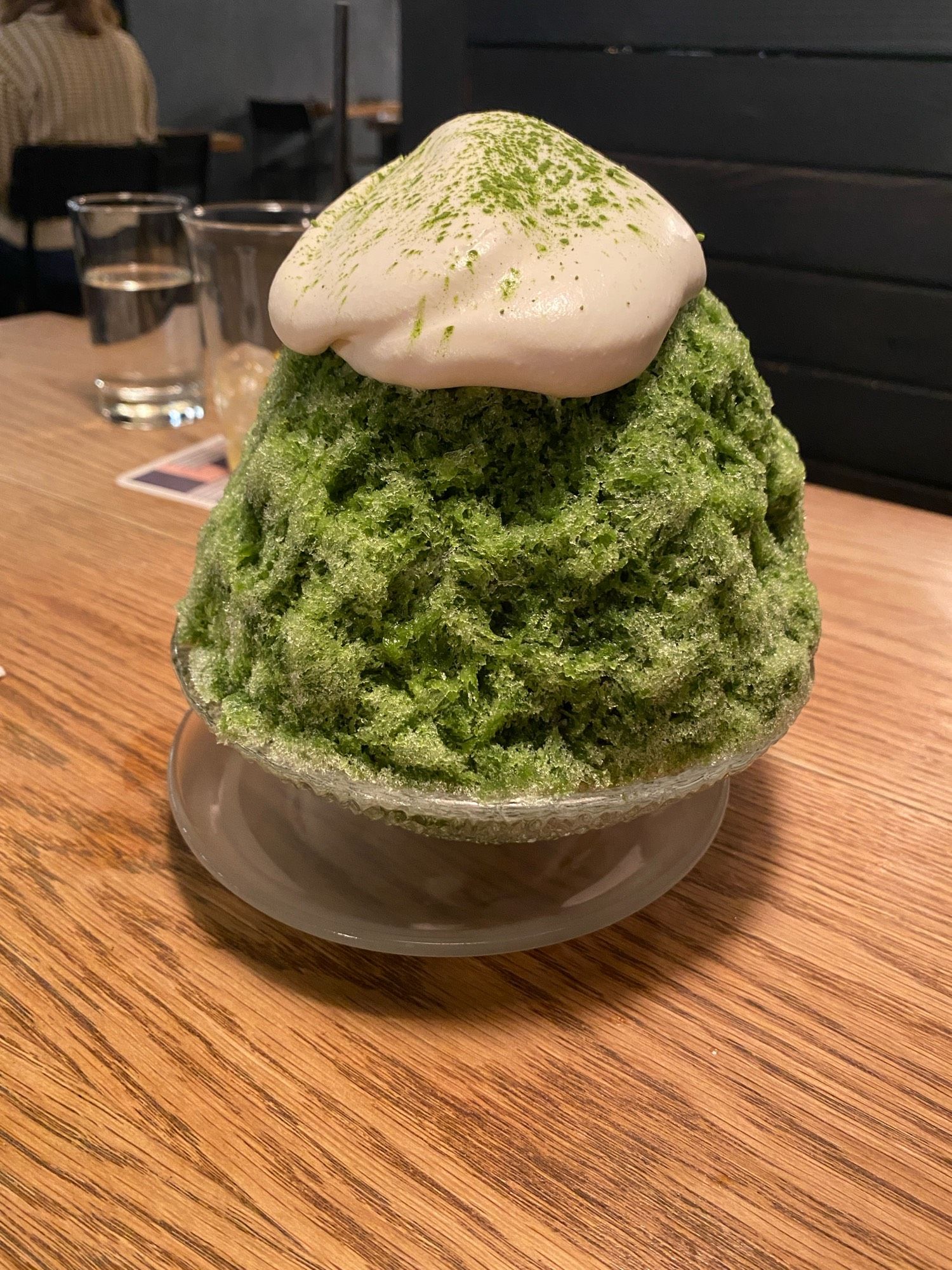 matcha shaved ice that looks like a moss covered rock, with a dollop of honey cream on top