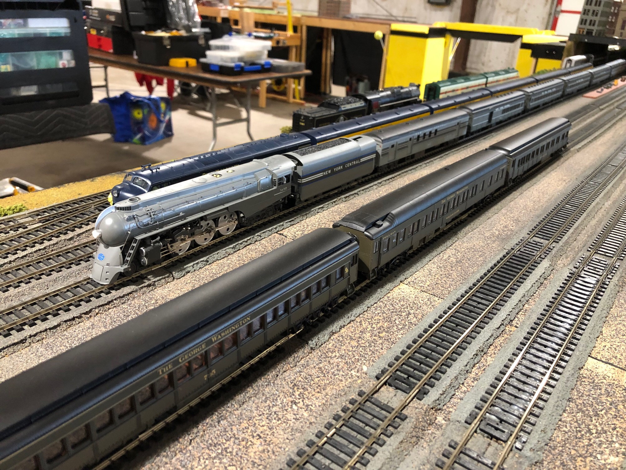 HO scale passenger trains staged in the yard and approaches of Union Station. The shot is focused on a New York Central streamlined Dreyfus Hudson in two tone grey, leading a train of NYC passenger cars.