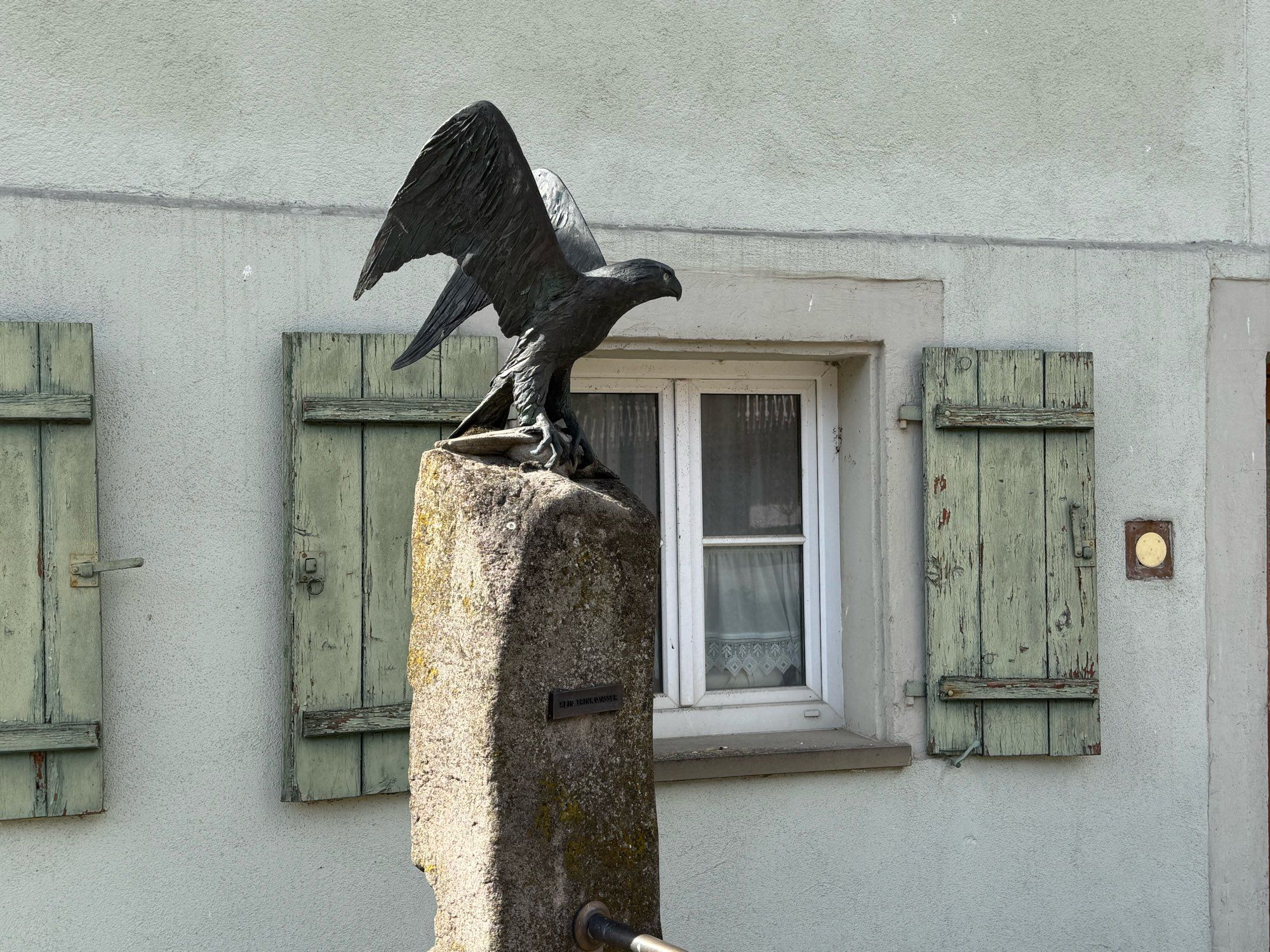 Dorfbrunnen mit Greifvogelskulptur -Adler