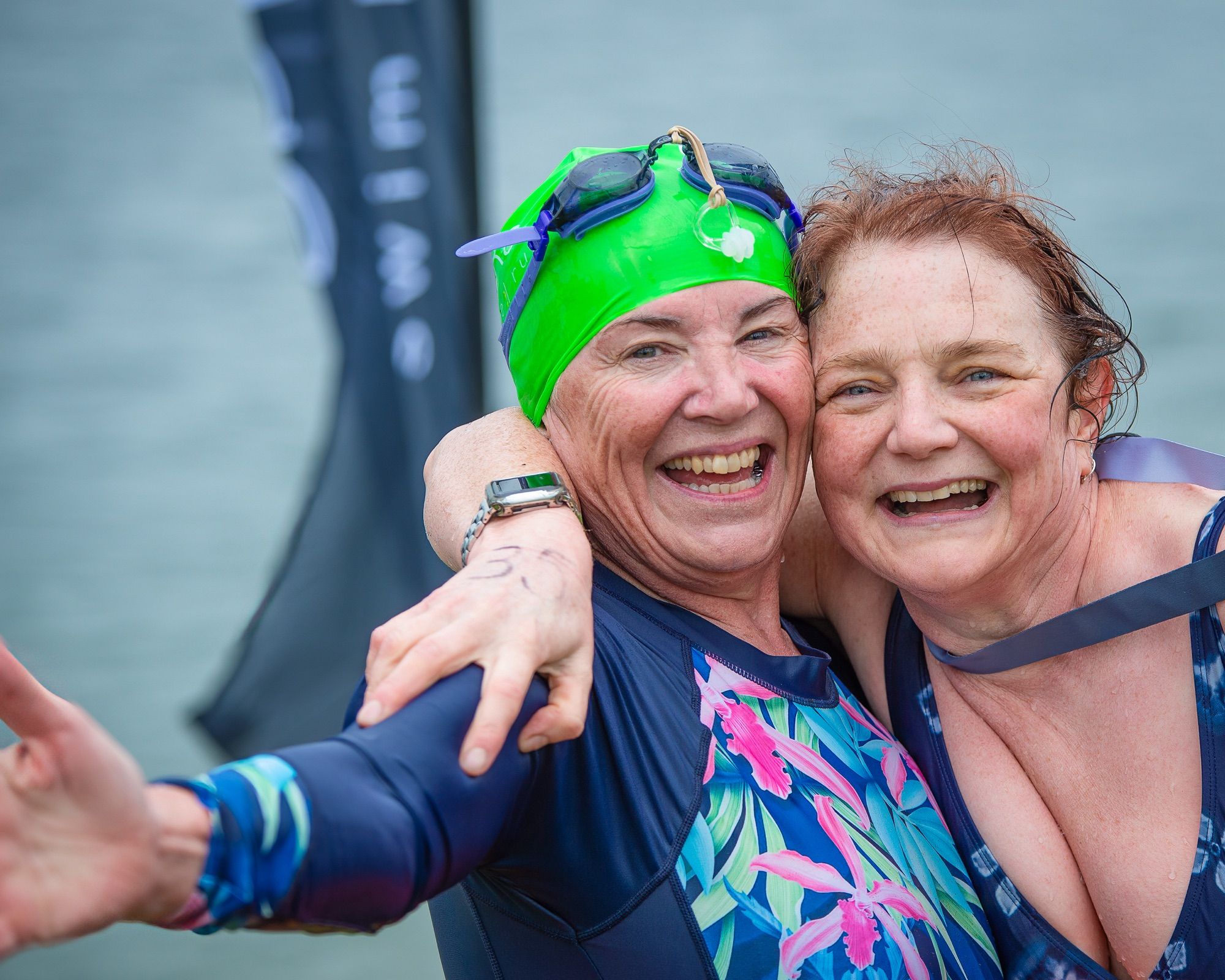 Two swimmers hug after completing their swim in the lake