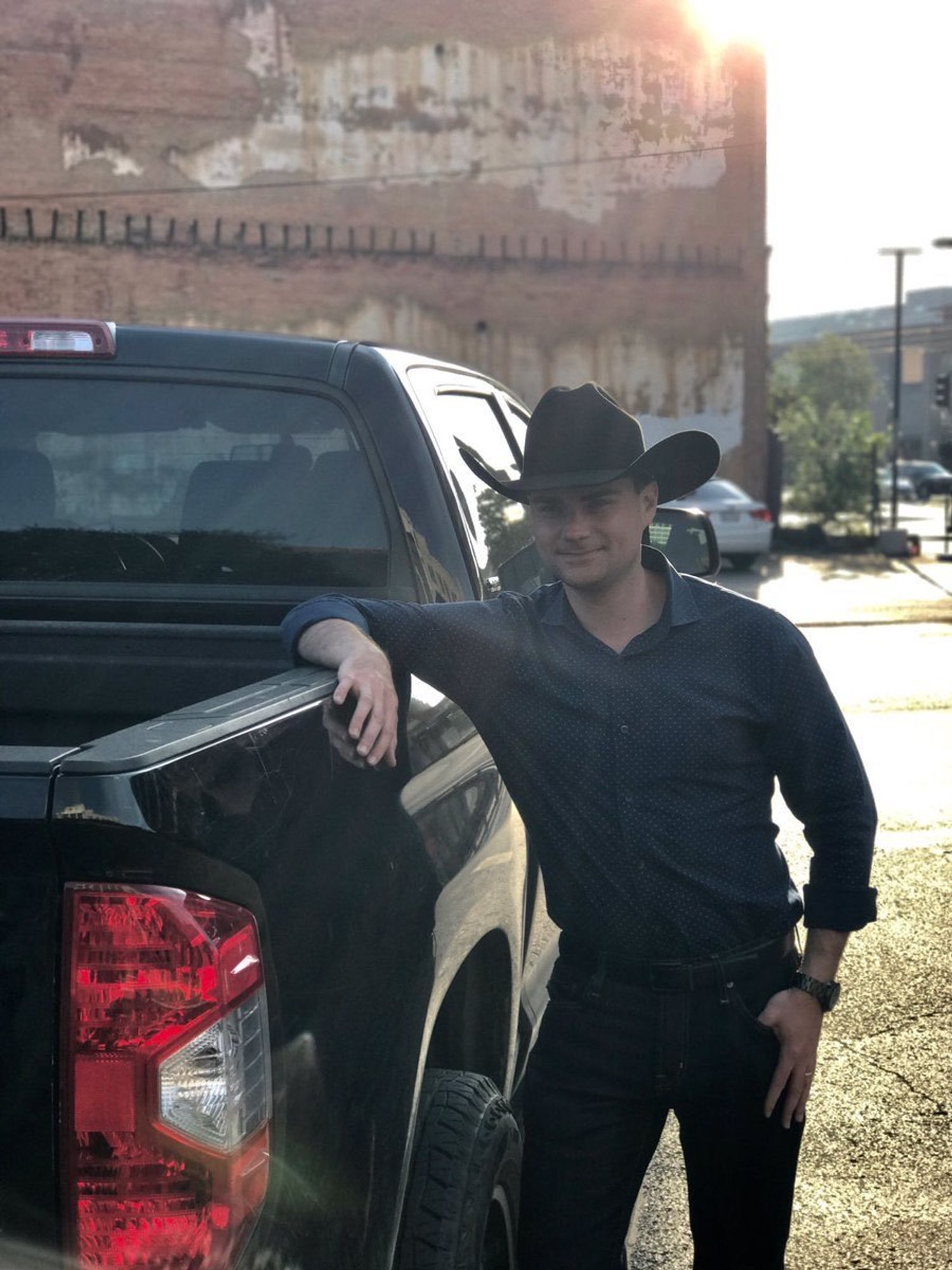 Ben Shapiro wearing a cowboy hat and standing next to his pickup truck