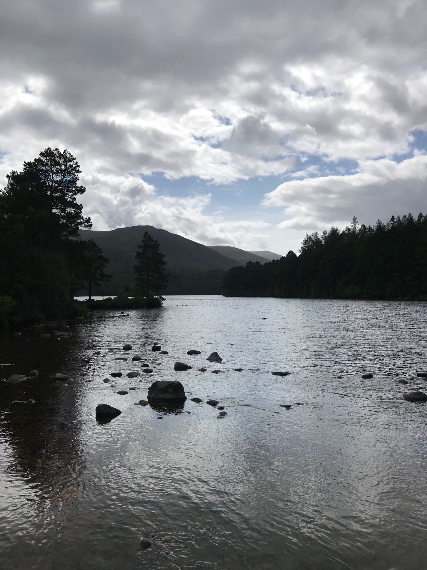 A landscape shot of Loch an Eilein in Scotland across the water with mountains in the distance