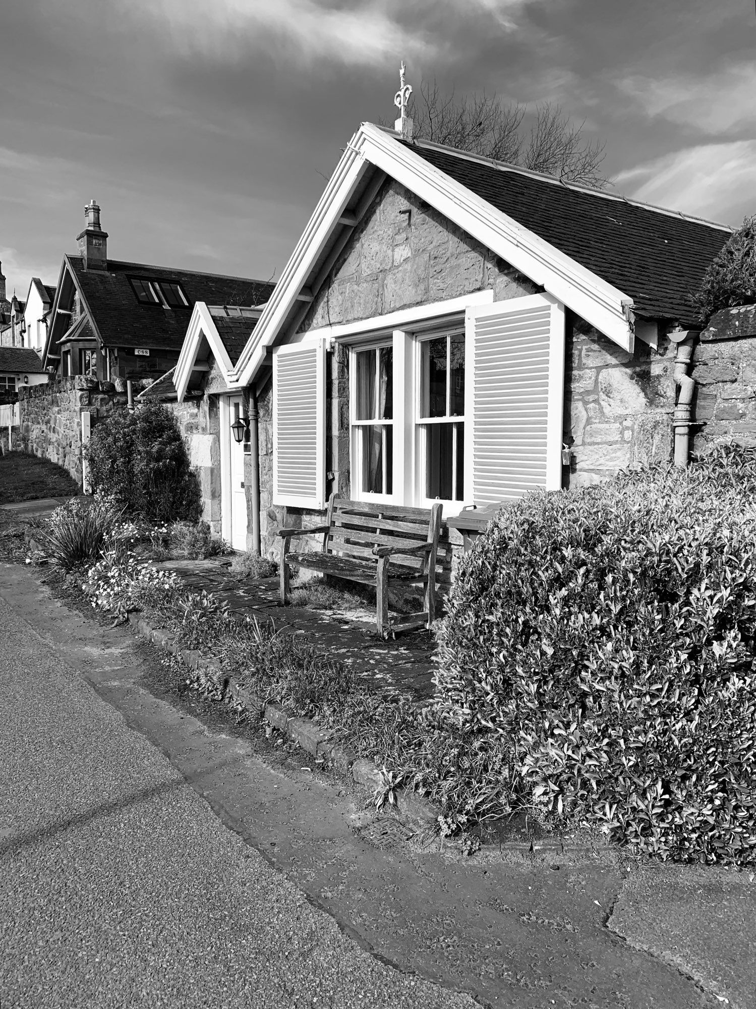 Black and white picture of a cottage with a white zig zag housing the roan of the roof, it reminds me of a giant lightning bolt