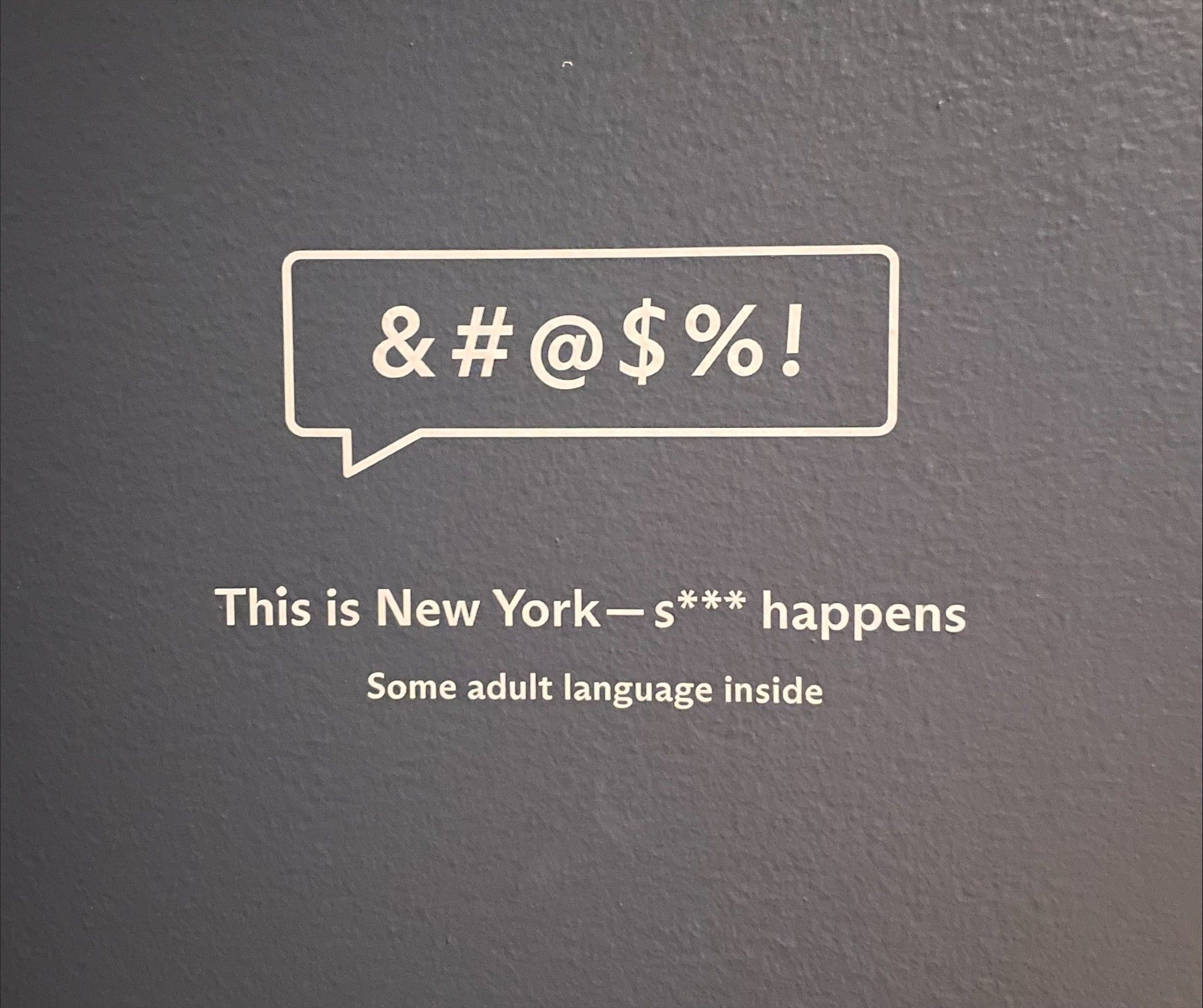 Adult language signage. It includes the following characters in a talk bubble: &#@&%!. Below that the text reads: This is New York — s*** happens. And below that reads: Some adult language inside.