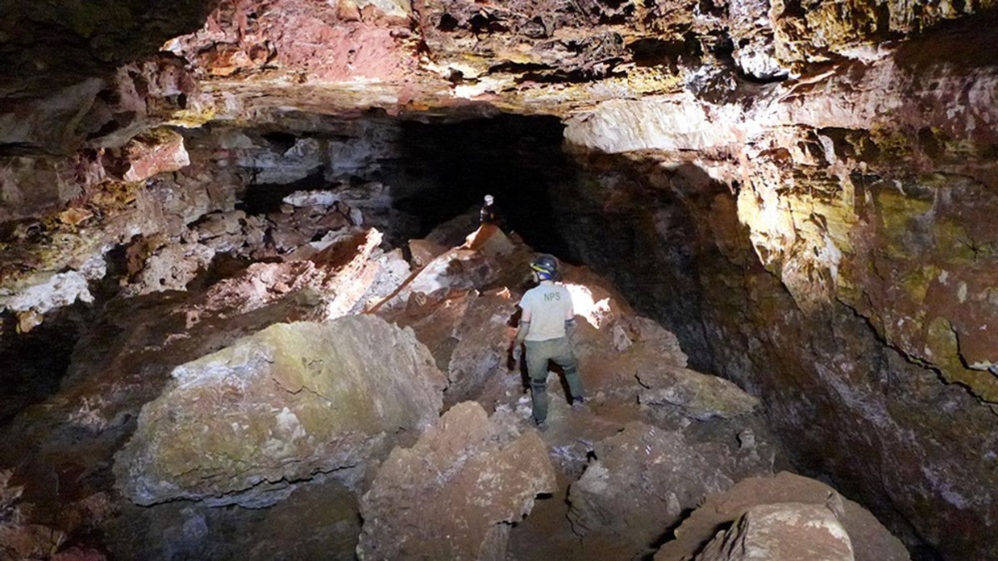 Two cave explorers stand in a large passageway in South Dakota's Wind Cave.