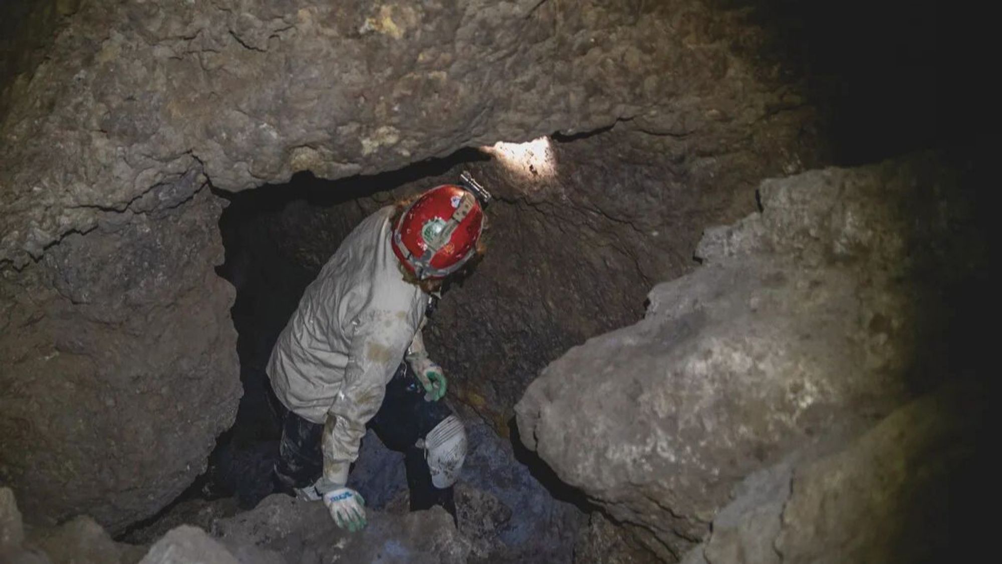 A caver wearing a helmet and light explores a Wyoming cave.