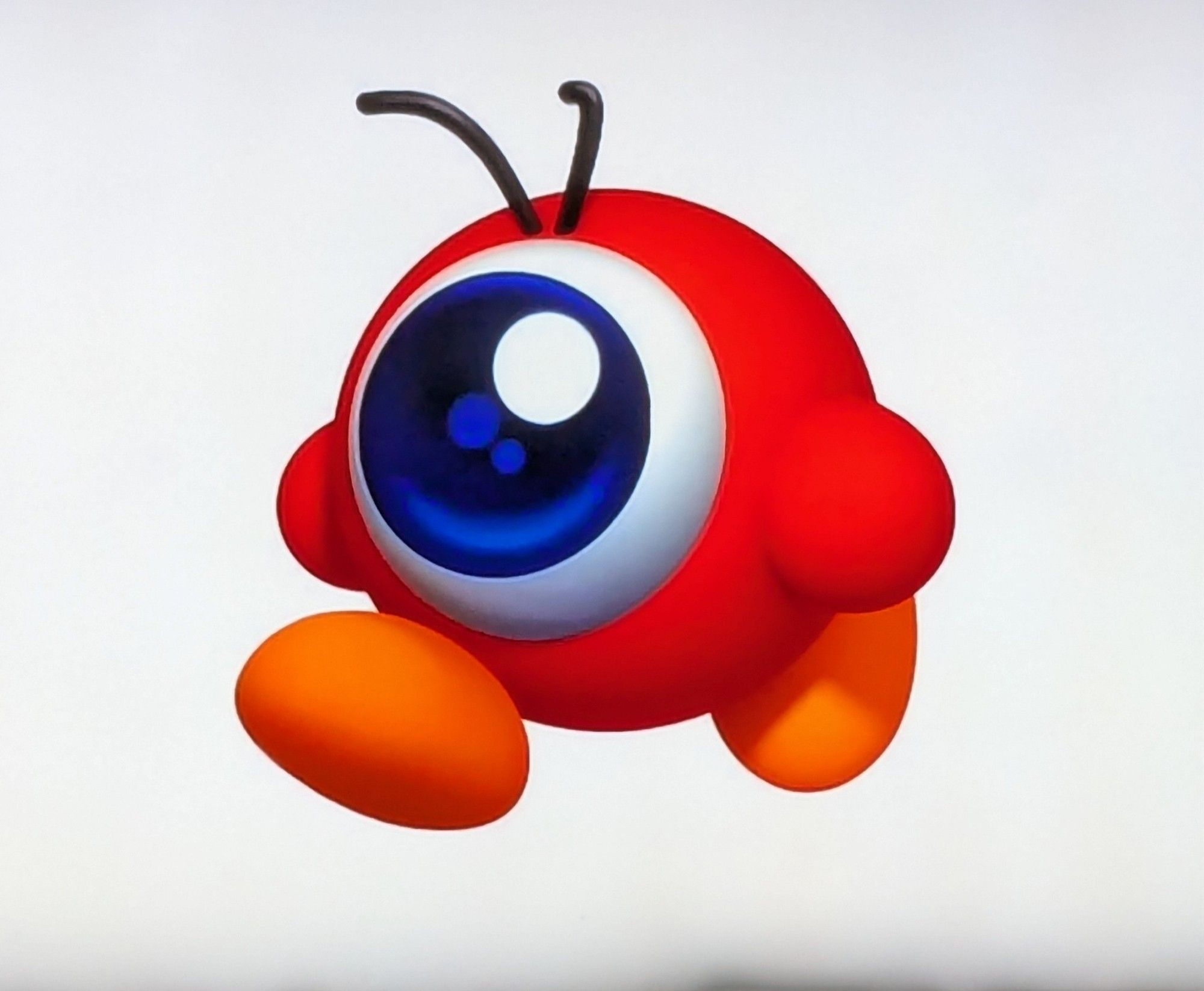 A pretty 3D render of a Waddle Doo from the Kirby series of games. A spherical little red guy with two orange feet, two arms, two little hairs on its head, and one big eyeball taking up most of its body. It's the same body type as Kirby.