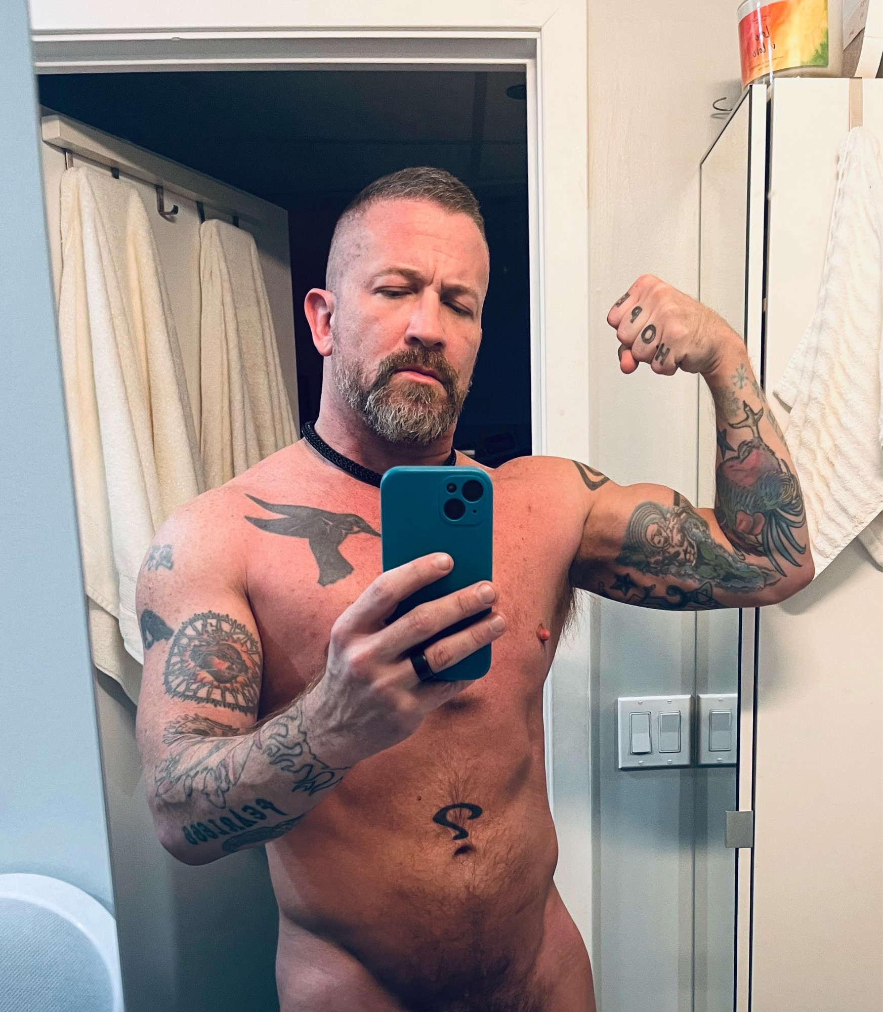 Coach is naked and flexing a bicep in another morning mirror selfie. This one is (mercifully?) cropped at his bush so his genitals aren’t exposed.