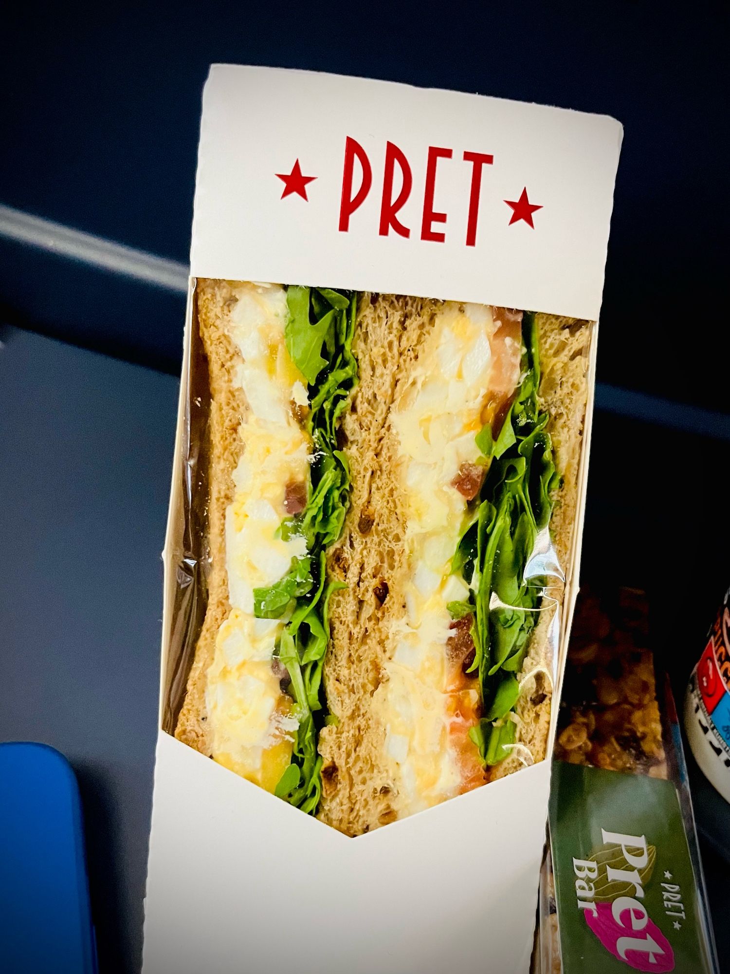 Das Bild zeigt ein verpacktes Sandwich mit Ei und Salat auf einem Klapptisch im ICE.