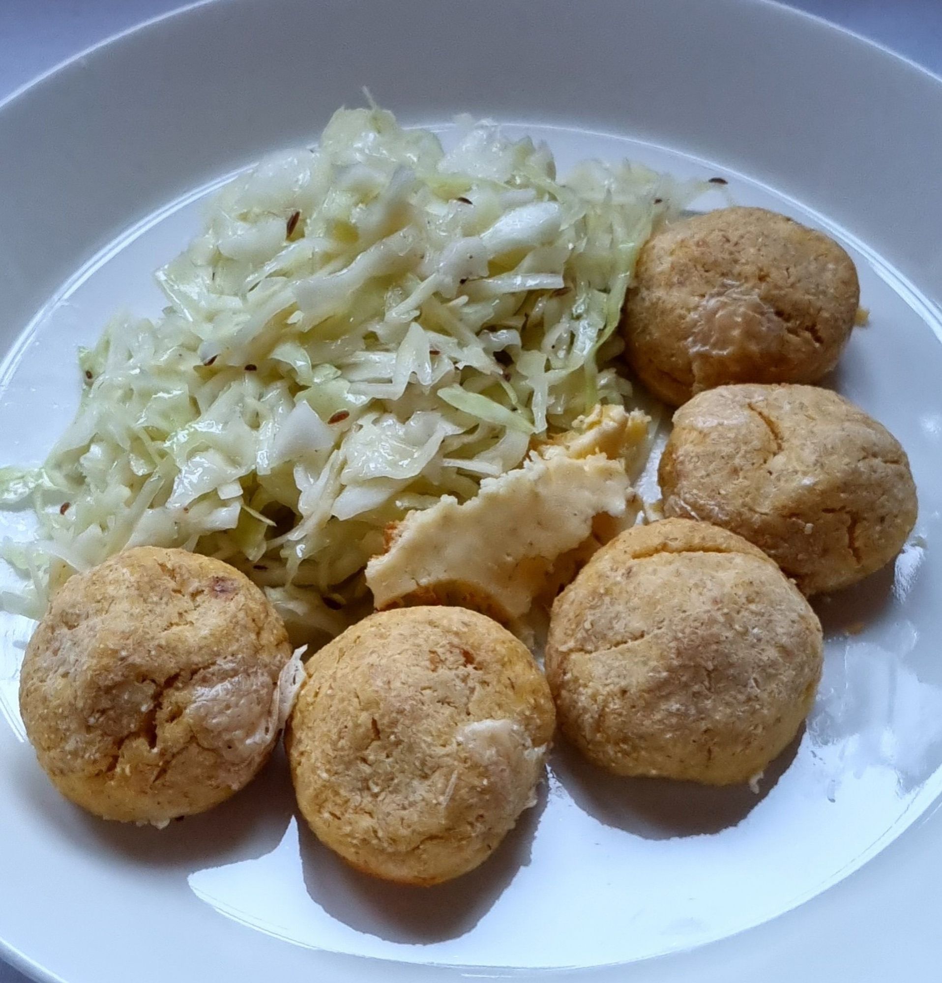 Ein Teller mit 5 ausgedünsteten Erdäpfelknödel mit lauwarmen Krautsalat