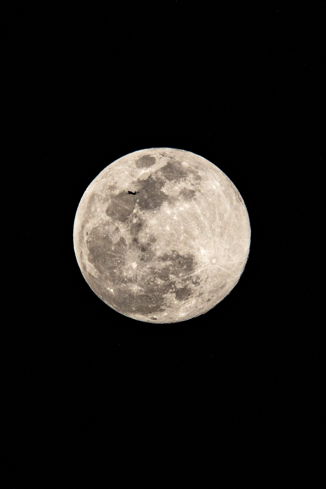 big full moon with a tiny tiny lil plane flying in front of it