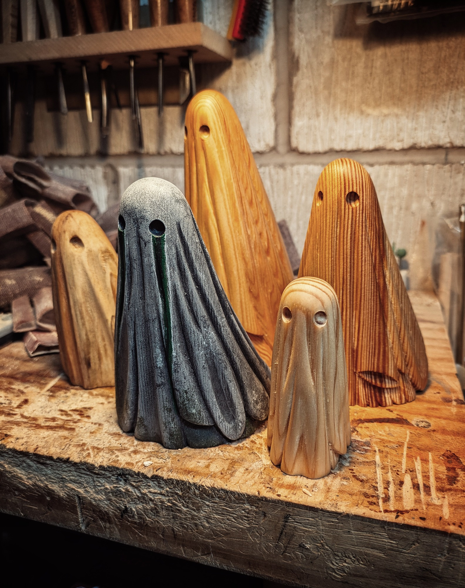 A cluster of wood carved sheet ghosts on a workbench.