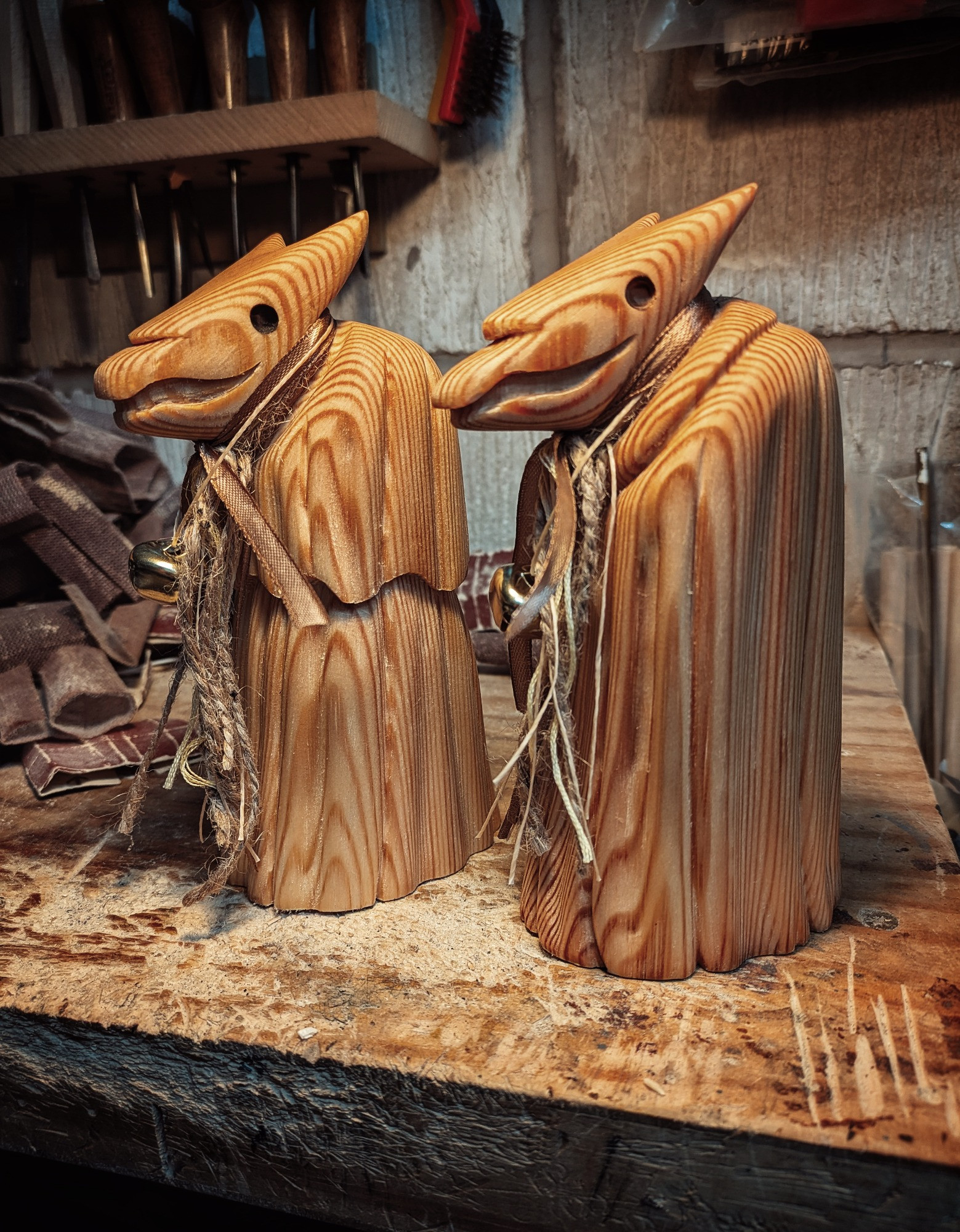 Two wood carved Mari Lywds on a workbench.