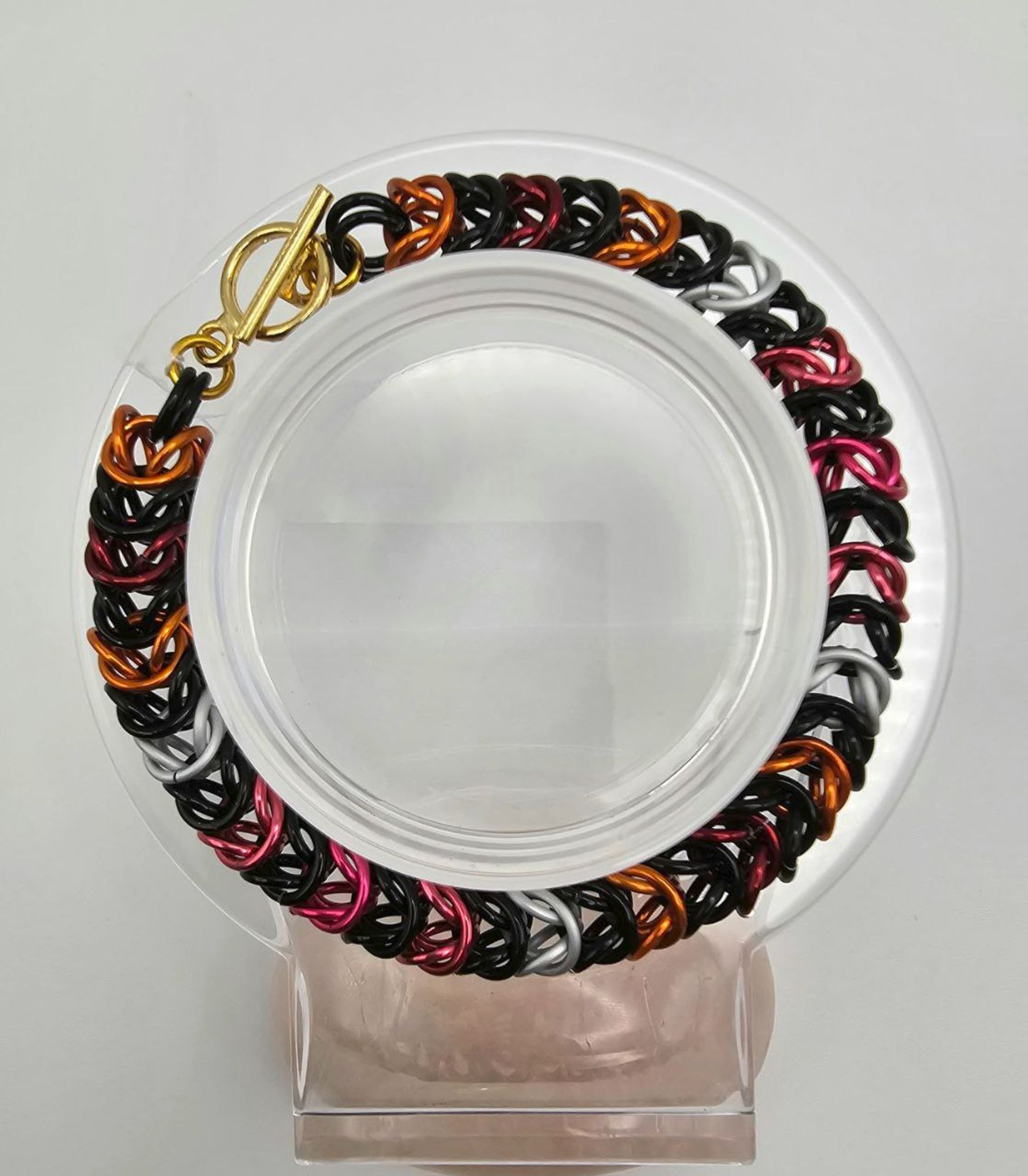 Lesbian punk themed box weave bracelet: black, orange, ref, white, pink, and dark pink rings.