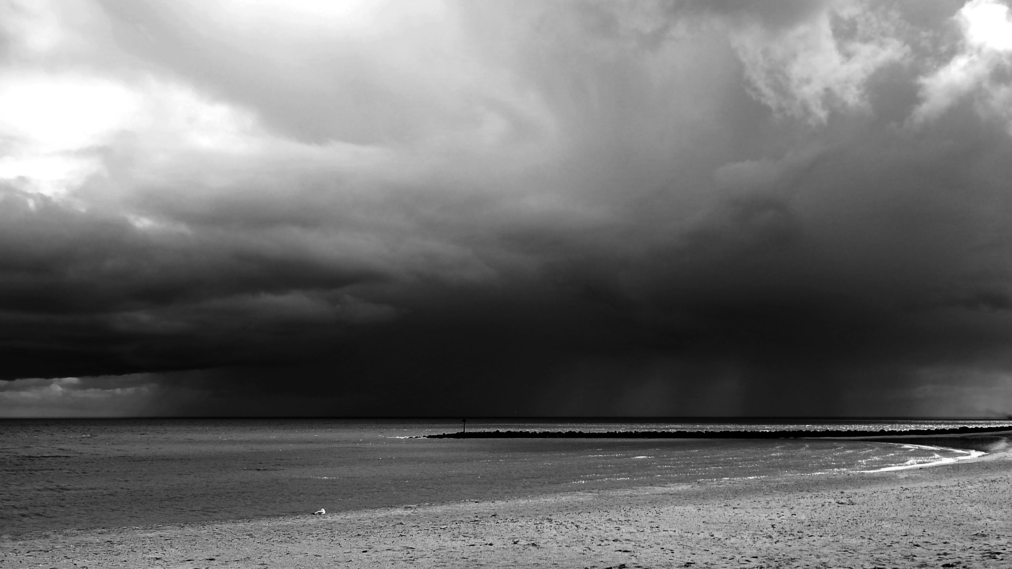 A Cloudbursts over the horizon on a calm sea.