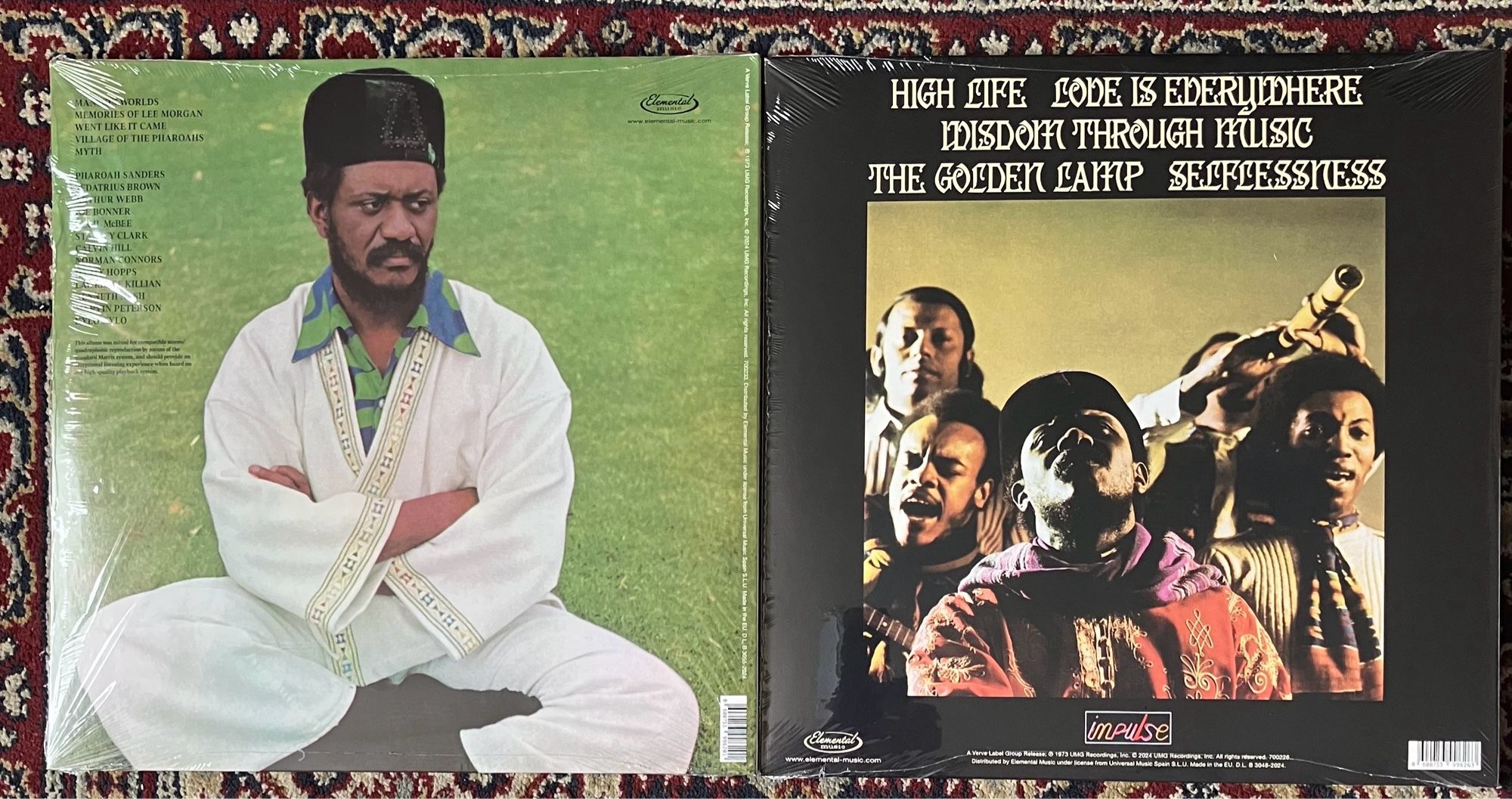 Photograph of Pharoah Sanders - Village Of The Pharoahs LP on the left and 
Pharoah Sanders - wisdom through music LP on the right. 
On the left Pharoah is dressed in a white outfit sitting cross legged on the grass. 
On the right is a group shot, they look very ‘in the moment’..