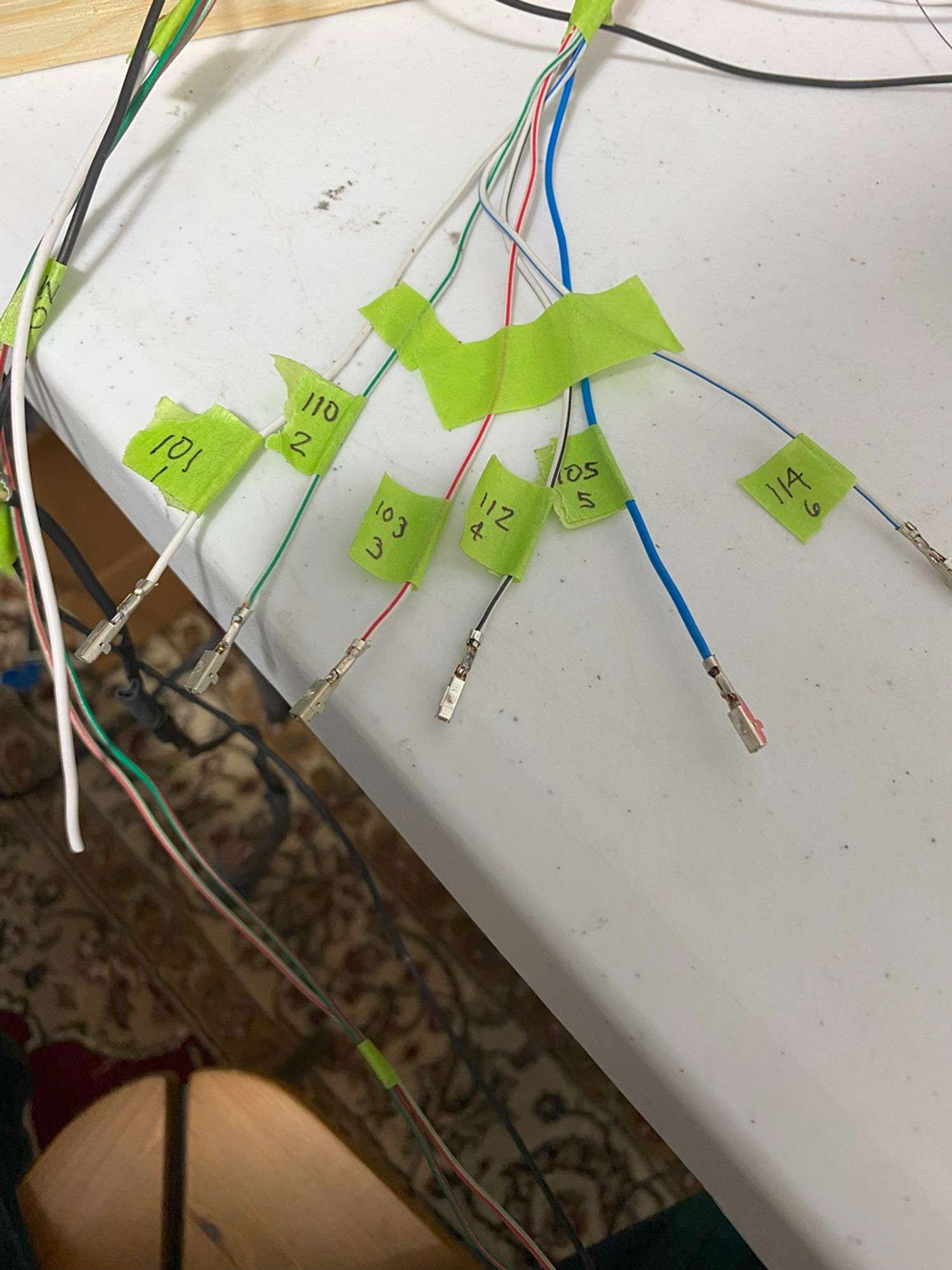 Pictured are six wires with green tape on each. The tape is attached as a label. Each wire has two labels.  One is a number to indicate which "pin" on the engine computer it needs to go to. The other number indicates which cylinder it goes to so I can test the circuit before adding it to the connector.