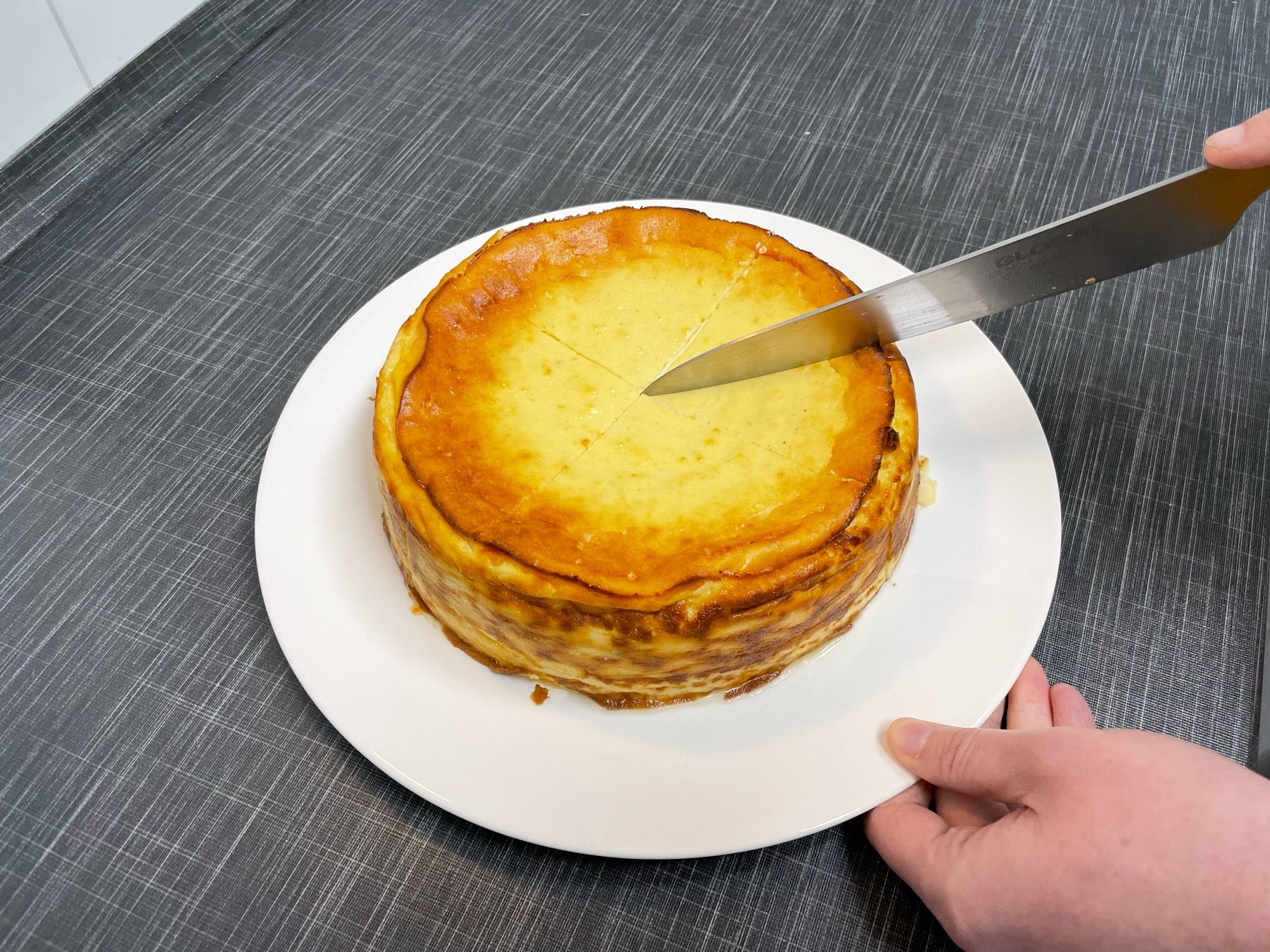 Auf einem Teller: Käsekuchen, der angeschnitten wird.