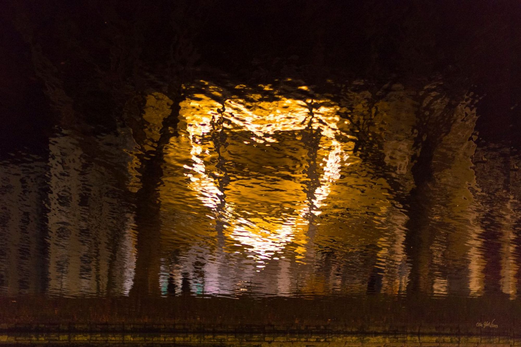 Eine herzförmige Lichtinstallation spiegelt sich im Wasser.