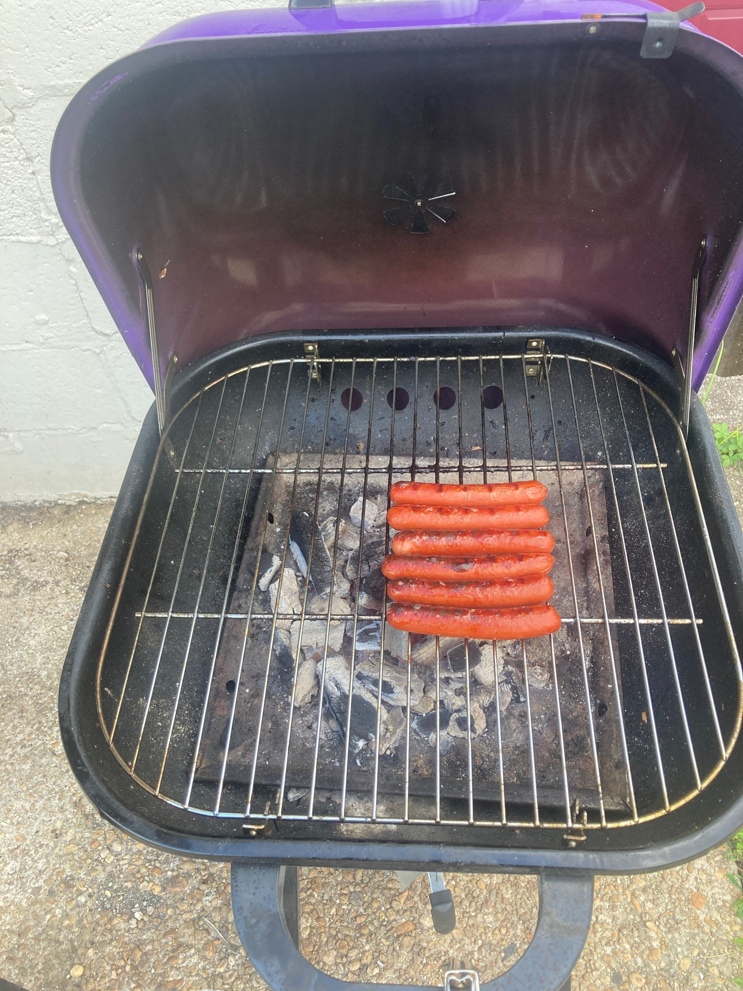 Six glizzys in a single column on a purple charcoal grill