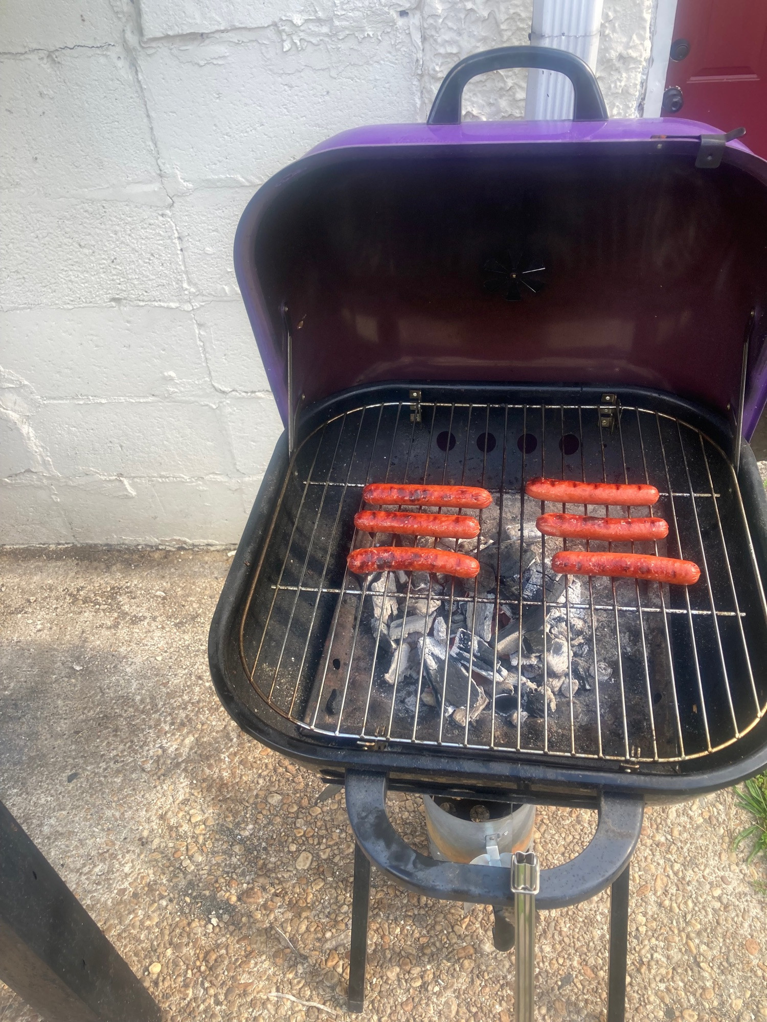 Two columns of 3 hot dogs (glizzys) on a purple charcoal grill