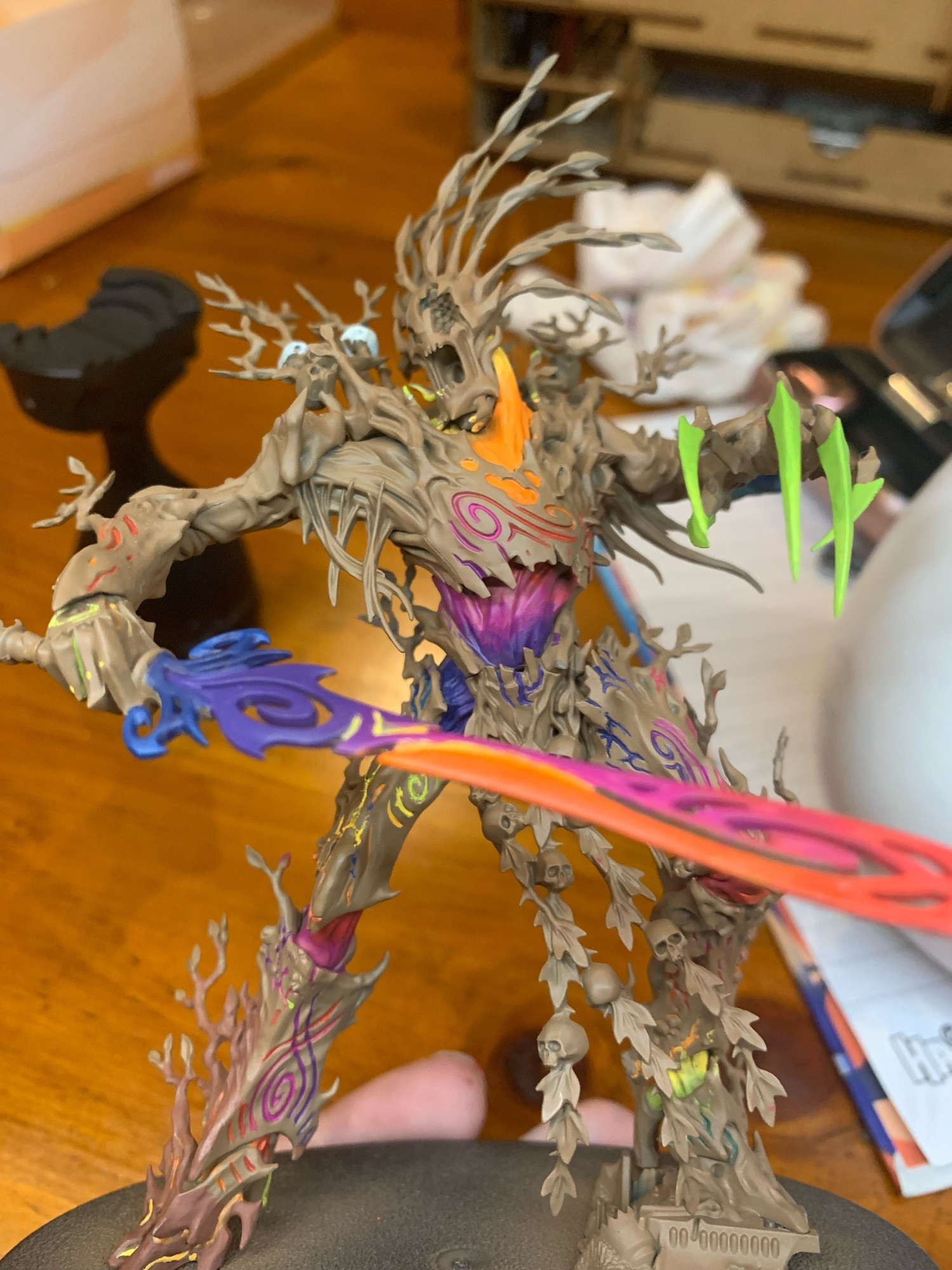 A humanoid tree mini holding a big sword. The mini has been undercoated brown and is being painted rainbow