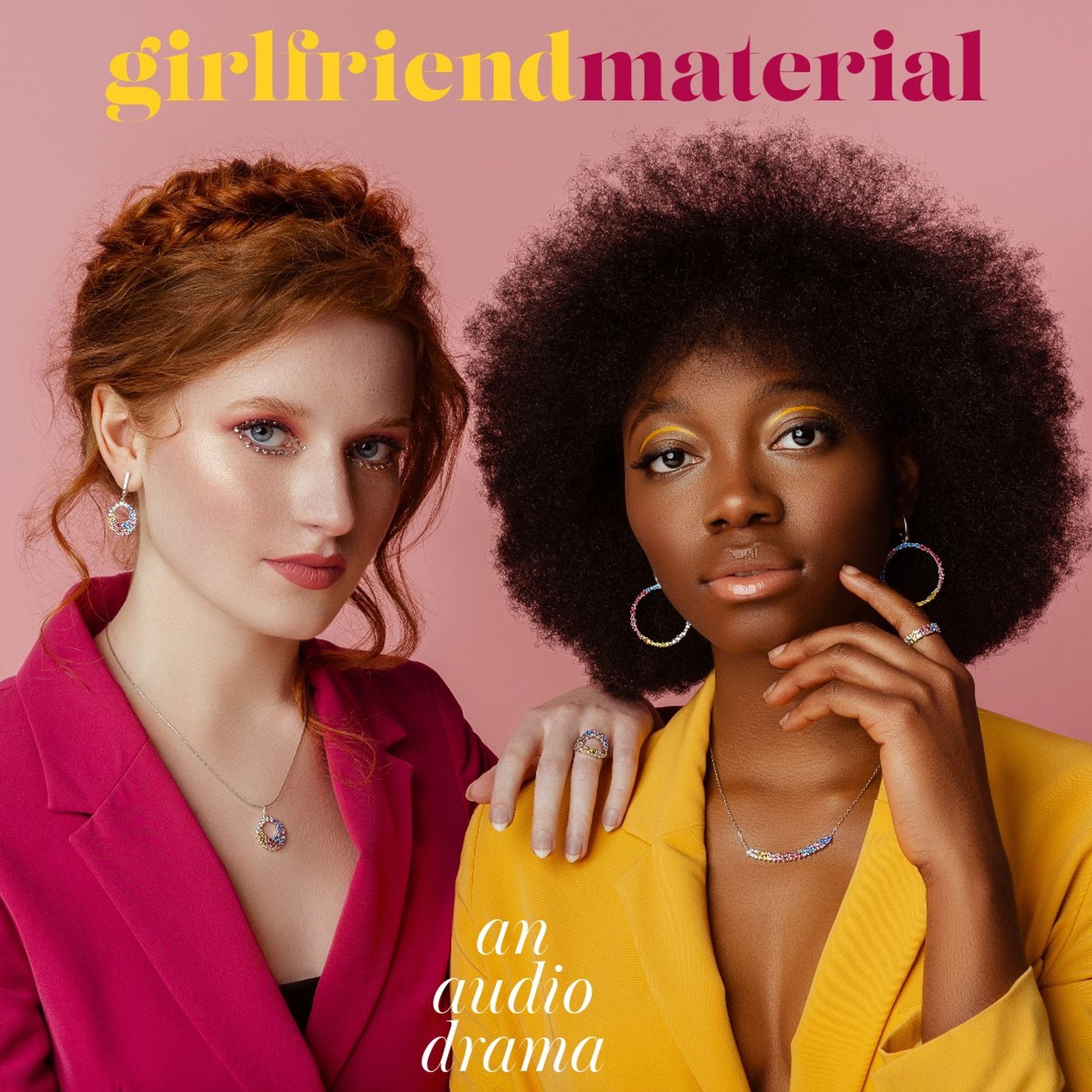 Two women look at the camera. On the left is a Caucausian redhead with a messy bun hairstyle in sparkly eye makeup and wearing a pink blazer. On the right is an African woman with an afro wearing stark yellow eyeliner, large round earrings, a yellow blazer, and delicate necklace.